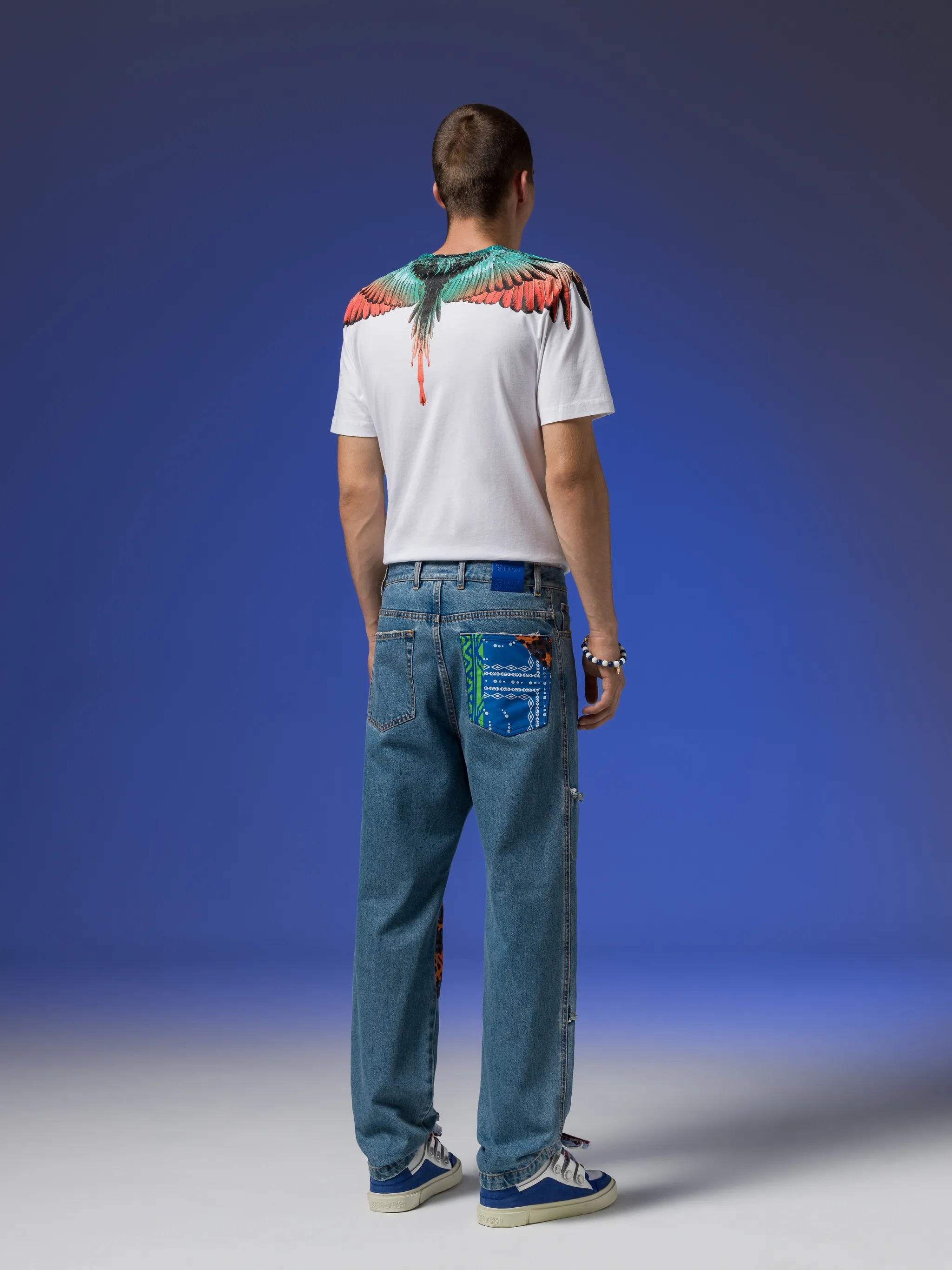 patchwork-detailing straight-leg jeans from Marcelo Burlon County of Milan featuring indigo blue, cotton blend, mid-wash, patchwork detailing, logo patch to the rear, straight leg, mid-rise, belt loops, front button and zip fastening and classic five pockets.