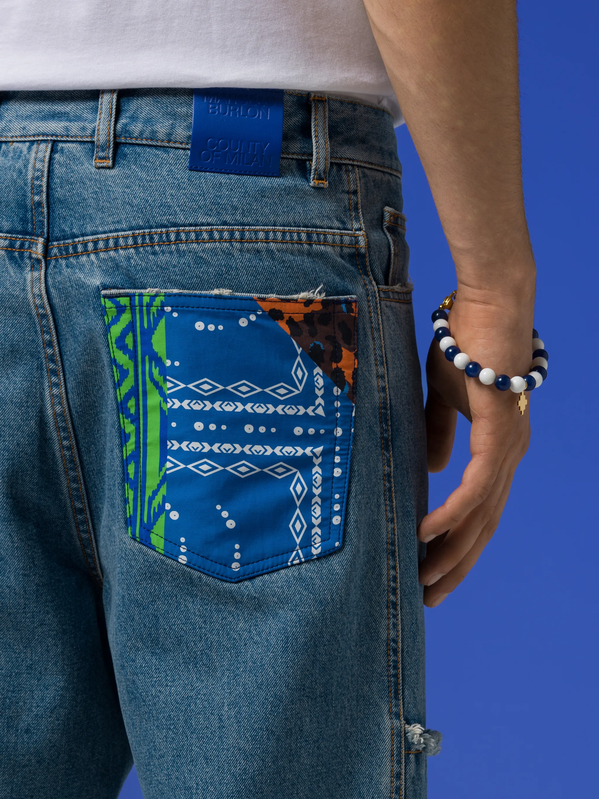patchwork-detailing straight-leg jeans from Marcelo Burlon County of Milan featuring indigo blue, cotton blend, mid-wash, patchwork detailing, logo patch to the rear, straight leg, mid-rise, belt loops, front button and zip fastening and classic five pockets.