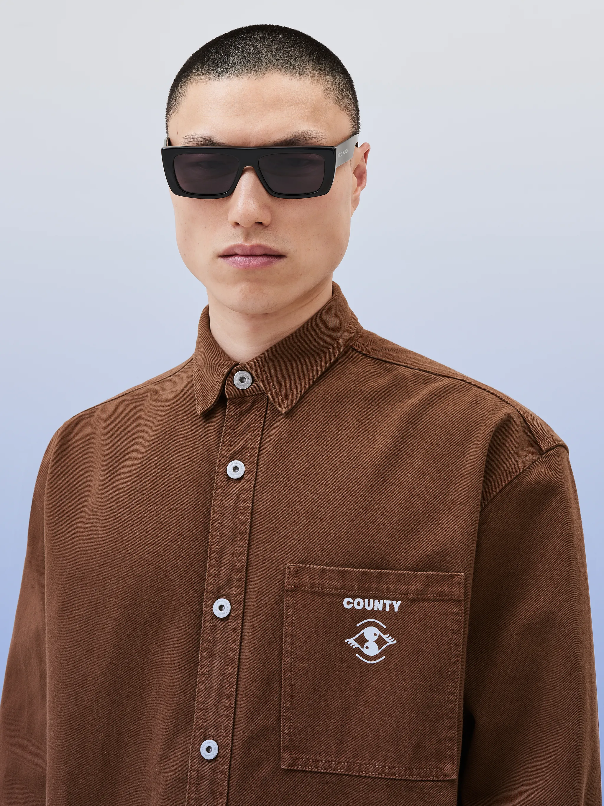 logo-print cotton shirt jacket from Marcelo Burlon County of Milan featuring chocolate brown, optical white, cotton, logo print at the chest, logo print to the rear, tonal stitching, classic collar, front button fastening, drop shoulder, long sleeves, buttoned cuffs, chest patch pocket and straight hem.