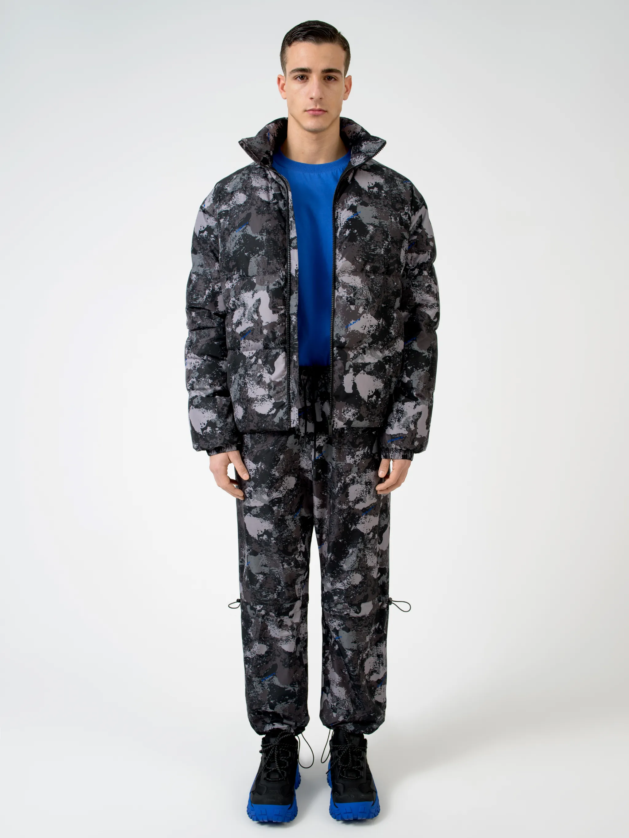 Tonal grey/royal blue camouflage print padded jacket from Marcelo Burlon County of Milan featuring camouflage print, stand-up collar, front zip fastening, two side patch pockets, long sleeves, elasticated cuffs and straight hem.
