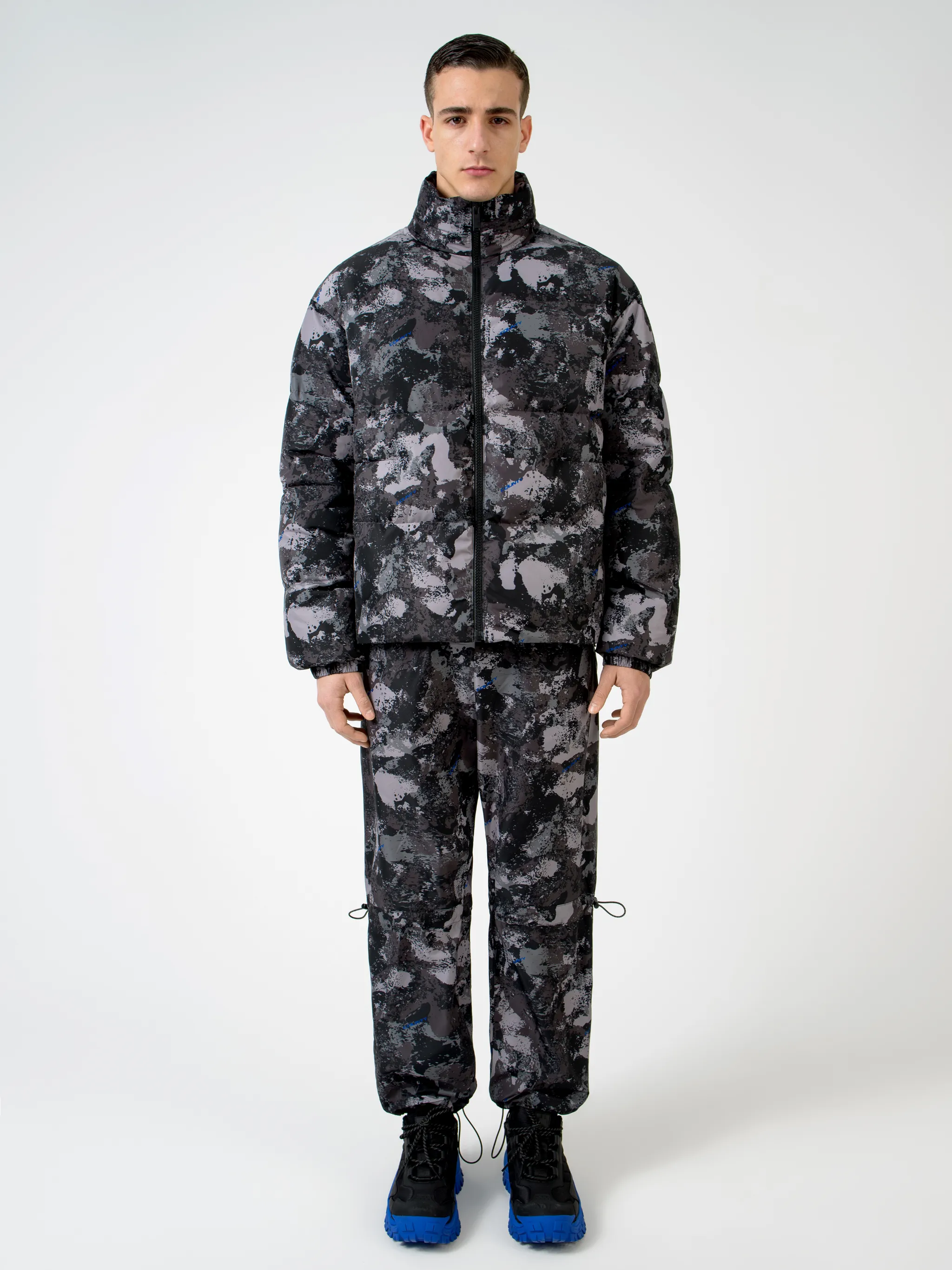 Tonal grey/royal blue camouflage print padded jacket from Marcelo Burlon County of Milan featuring camouflage print, stand-up collar, front zip fastening, two side patch pockets, long sleeves, elasticated cuffs and straight hem.
