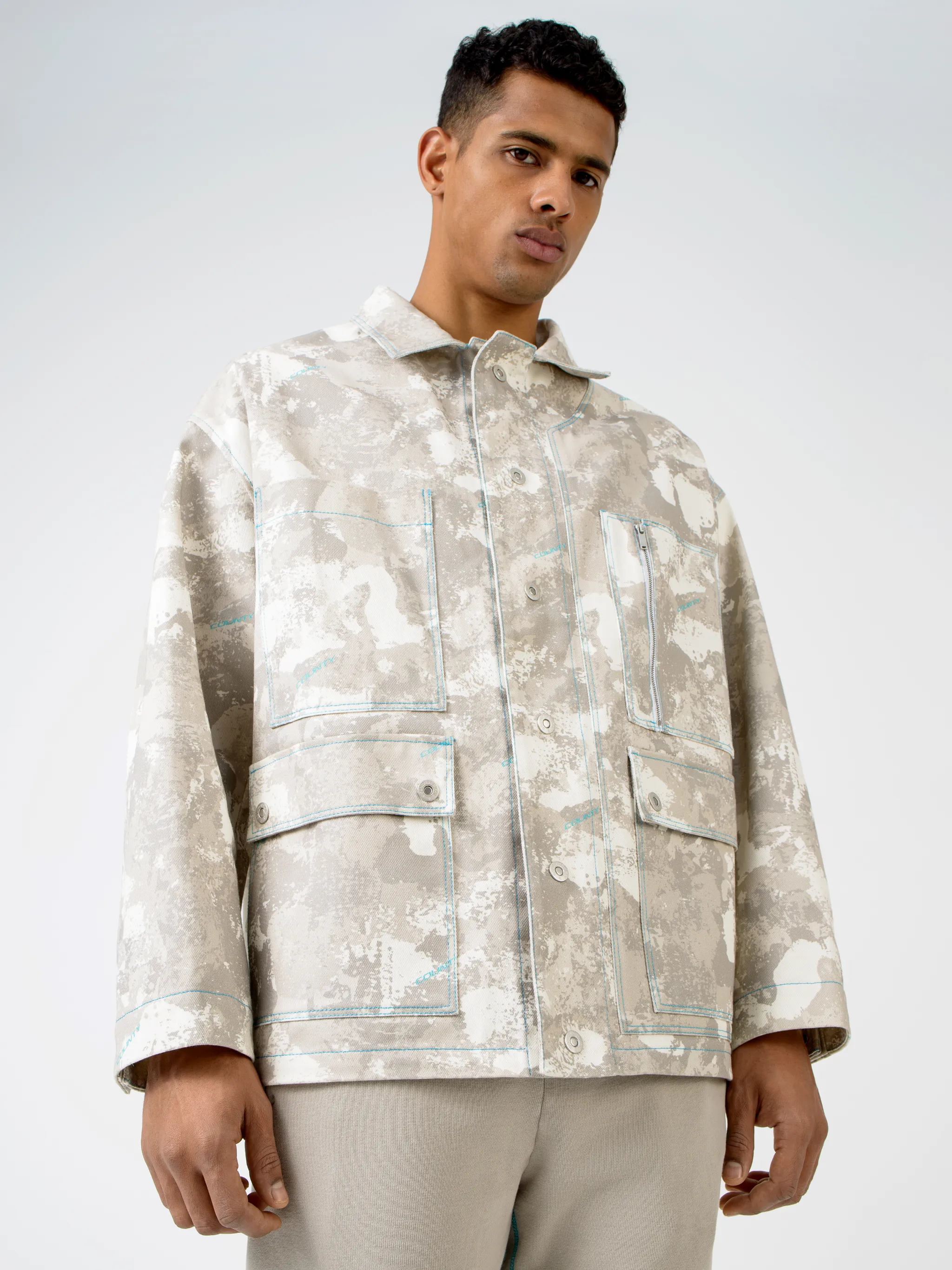 Tonal-beige cotton camouflage print military jacket from Marcelo Burlon County of Milan featuring camouflage print, classic collar, front button fastening, chest patch pocket, zip-fastening chest pocket, two side button-fastening pockets, long sleeves, buttoned cuffs and straight hem.