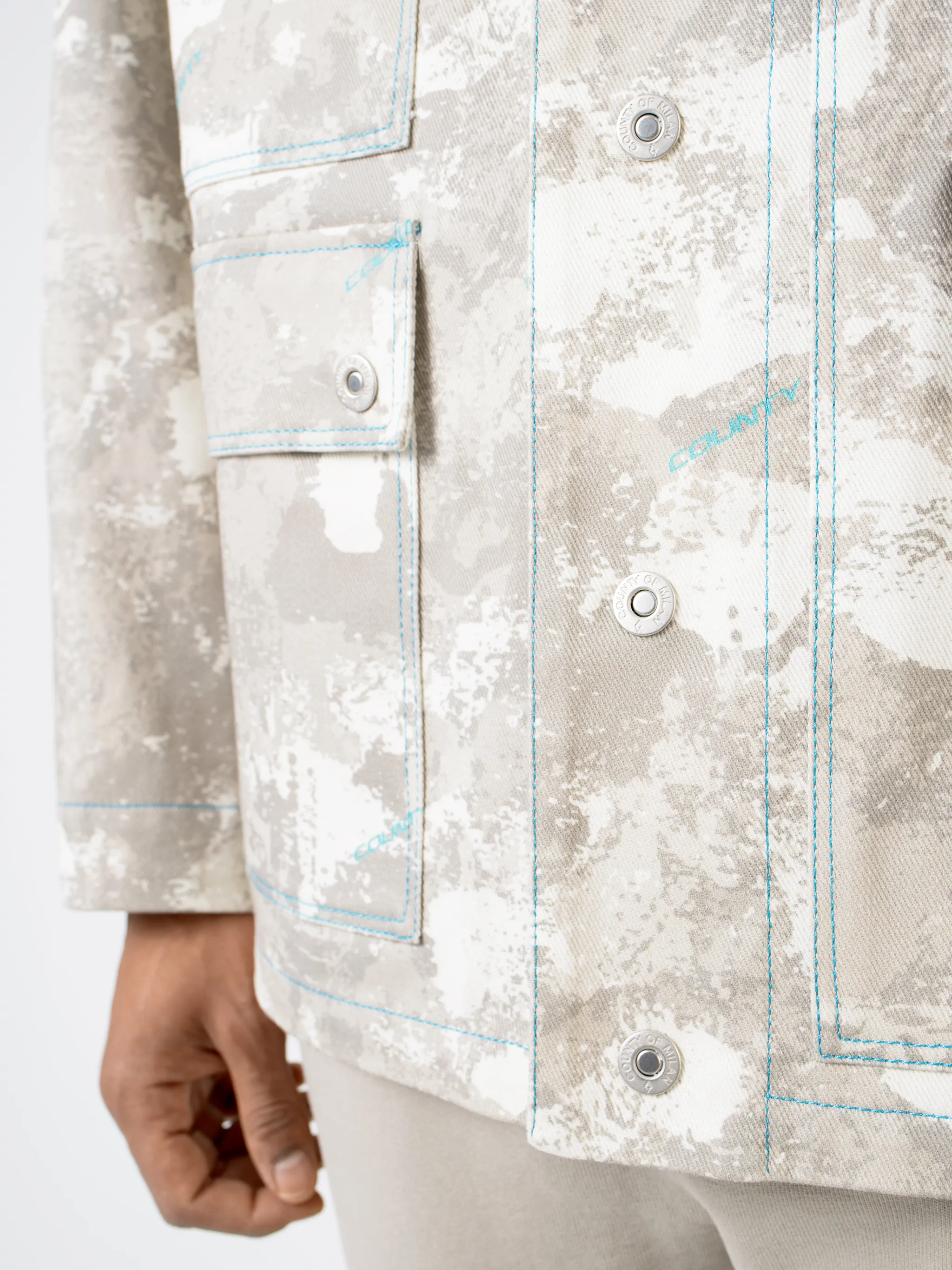 Tonal-beige cotton camouflage print military jacket from Marcelo Burlon County of Milan featuring camouflage print, classic collar, front button fastening, chest patch pocket, zip-fastening chest pocket, two side button-fastening pockets, long sleeves, buttoned cuffs and straight hem.