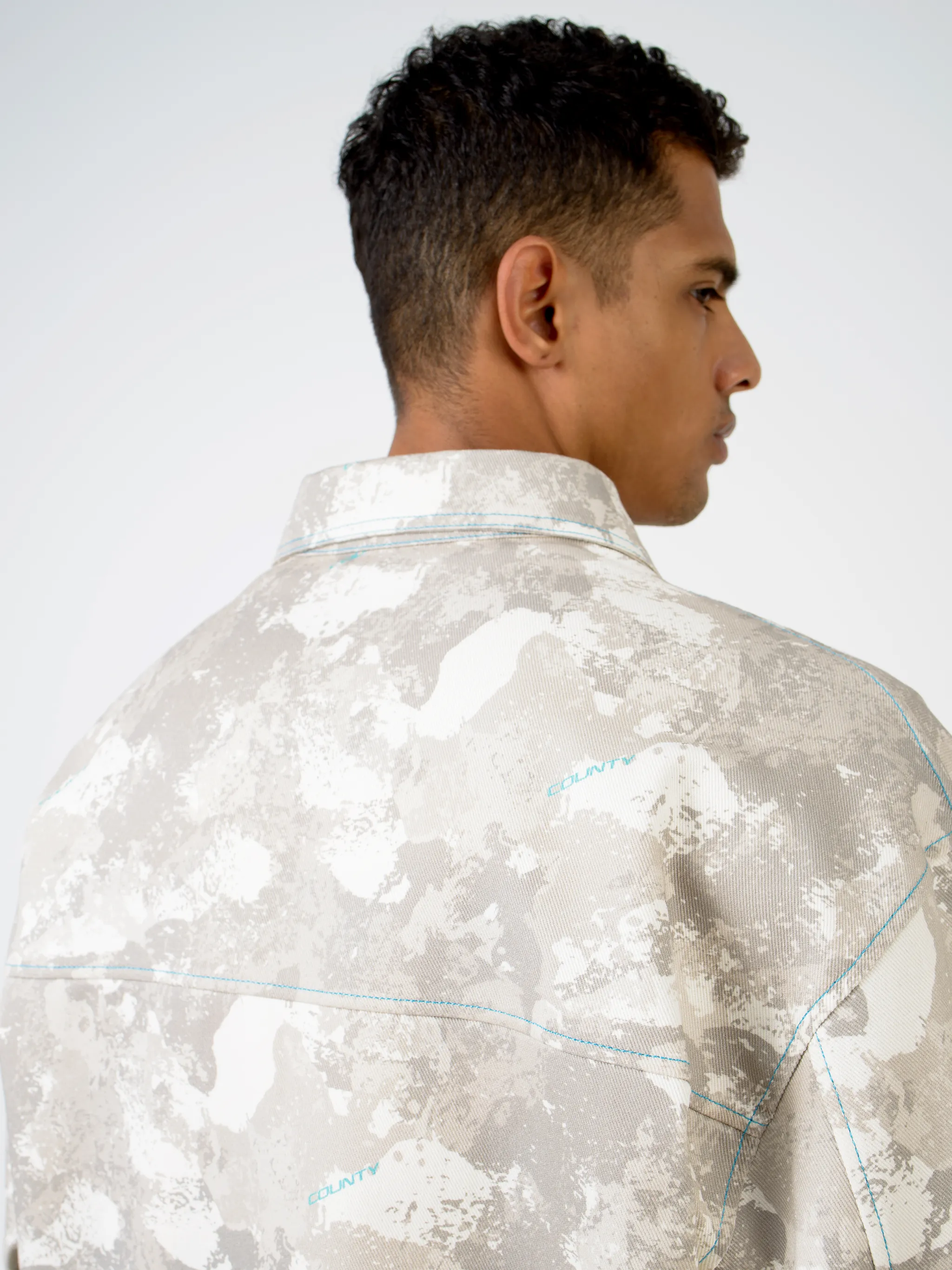 Tonal-beige cotton camouflage print military jacket from Marcelo Burlon County of Milan featuring camouflage print, classic collar, front button fastening, chest patch pocket, zip-fastening chest pocket, two side button-fastening pockets, long sleeves, buttoned cuffs and straight hem.