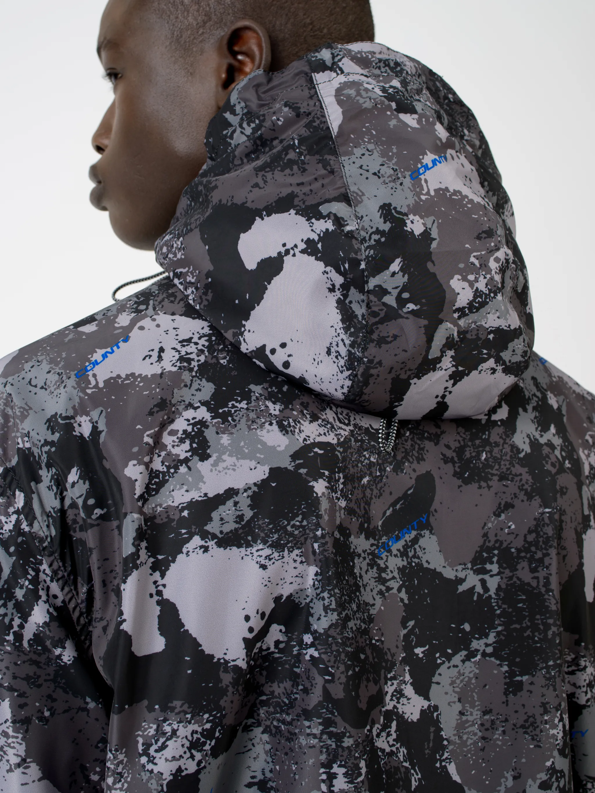 Tonal grey/royal blue camouflage print hooded windbreaker from Marcelo Burlon County of Milan featuring camouflage print, drawstring hood, front zip fastening, two side patch pockets, long sleeves and drawstring hem.