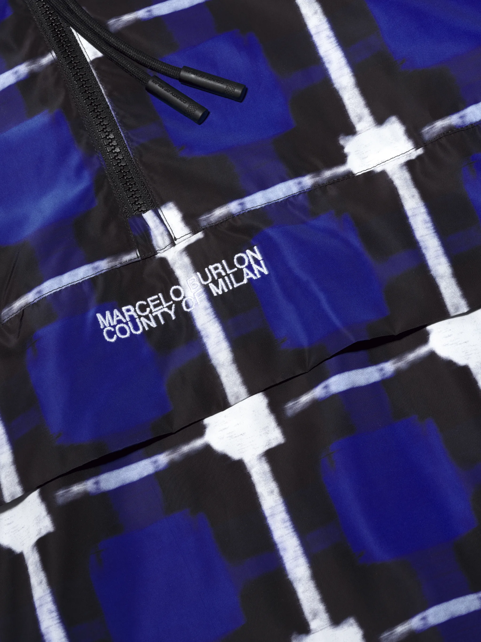 Blue and white check raincoat jacket from Marcelo Burlon County of Milan featuring drawstring hood, half front zip fastening, embroidered logo to the front, zip-fastening pocket, long sleeves and elasticated cuffs.