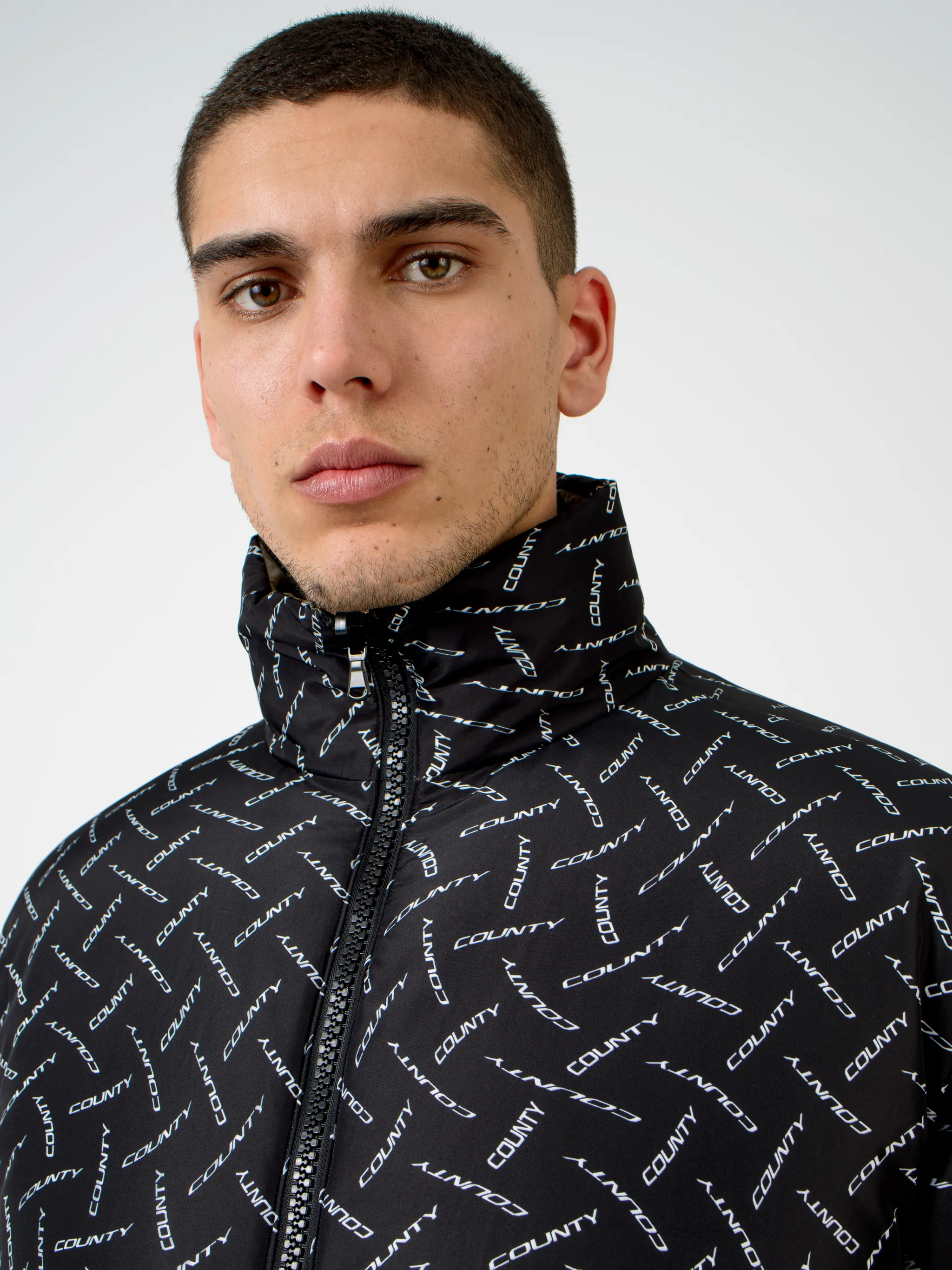 Black/white County logo print padded jacket from Marcelo Burlon County of Milan featuring all-over logo print, padded design, high neck, front zip fastening, two side patch pockets, long sleeves and straight hem.