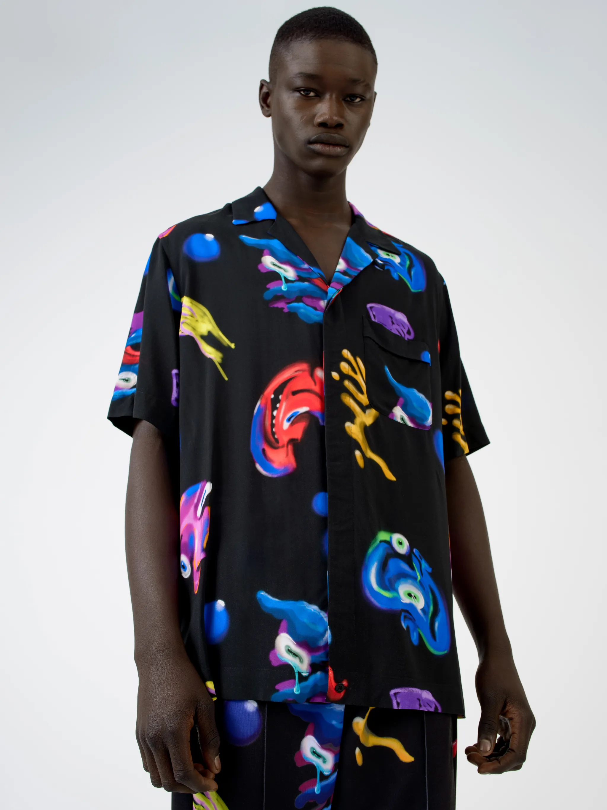 Black/multicolour Crazy Faces print shirt from Marcelo Burlon County of Milan featuring all-over logo print, spread collar, concealed front fastening, short sleeves and straight hem.