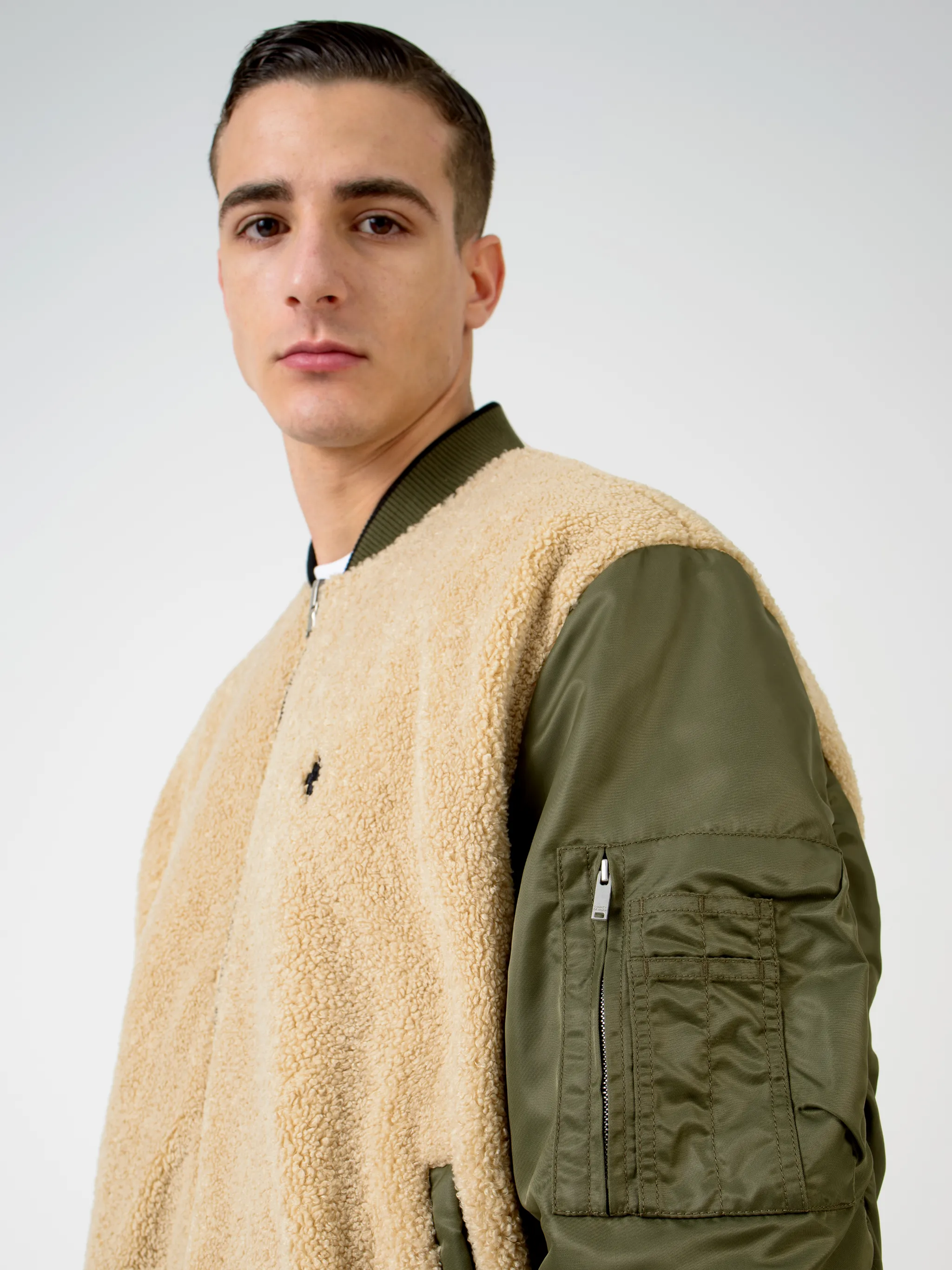 Army green/beige/black reversible panelled bomber jacket from Marcelo Burlon County of Milan featuring reversible, panelled design, embroidered logo to the rear, embroidered logo at the chest, ruched detailing, long sleeves, front zip fastening, two side slit pockets and ribbed edge.