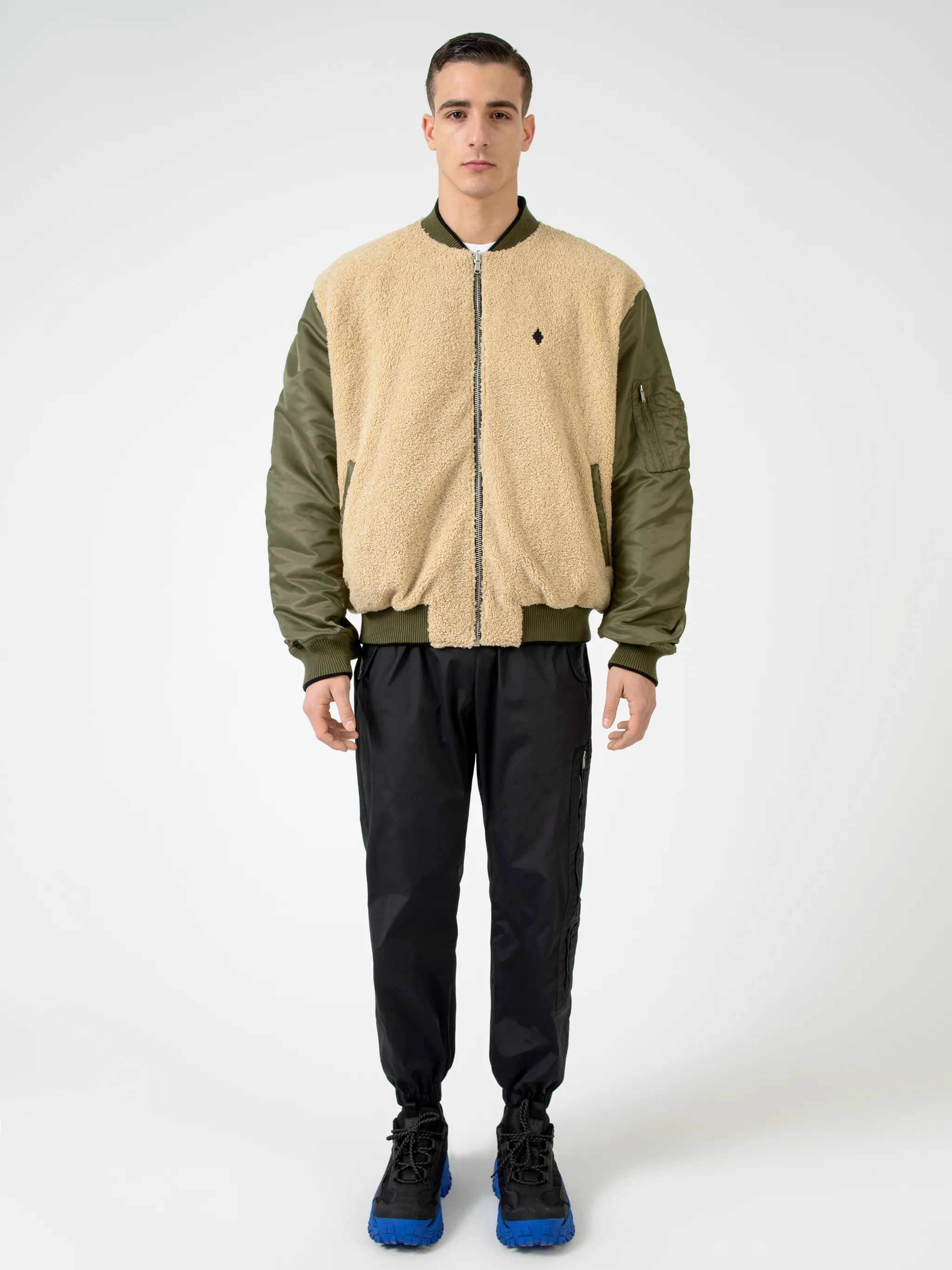 Army green/beige/black reversible panelled bomber jacket from Marcelo Burlon County of Milan featuring reversible, panelled design, embroidered logo to the rear, embroidered logo at the chest, ruched detailing, long sleeves, front zip fastening, two side slit pockets and ribbed edge.