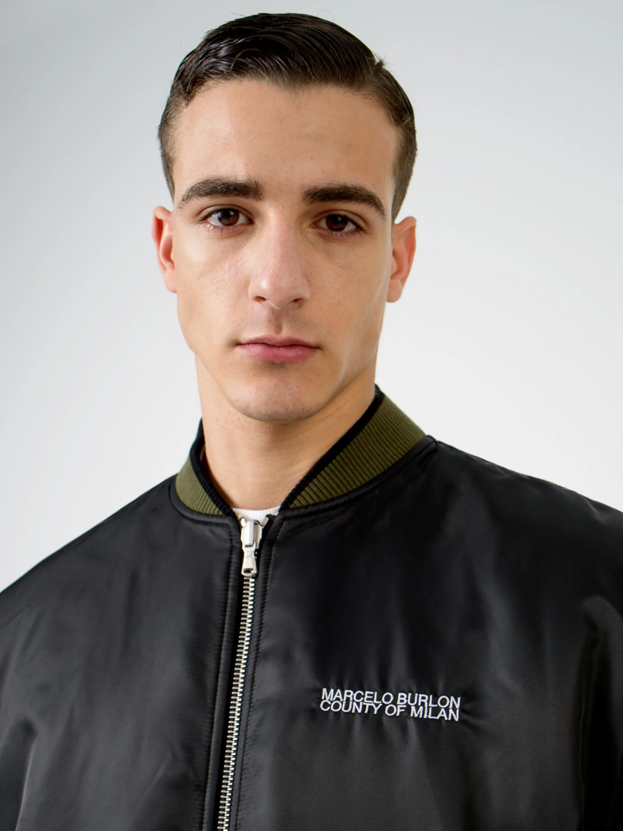 Army green/beige/black reversible panelled bomber jacket from Marcelo Burlon County of Milan featuring reversible, panelled design, embroidered logo to the rear, embroidered logo at the chest, ruched detailing, long sleeves, front zip fastening, two side slit pockets and ribbed edge.