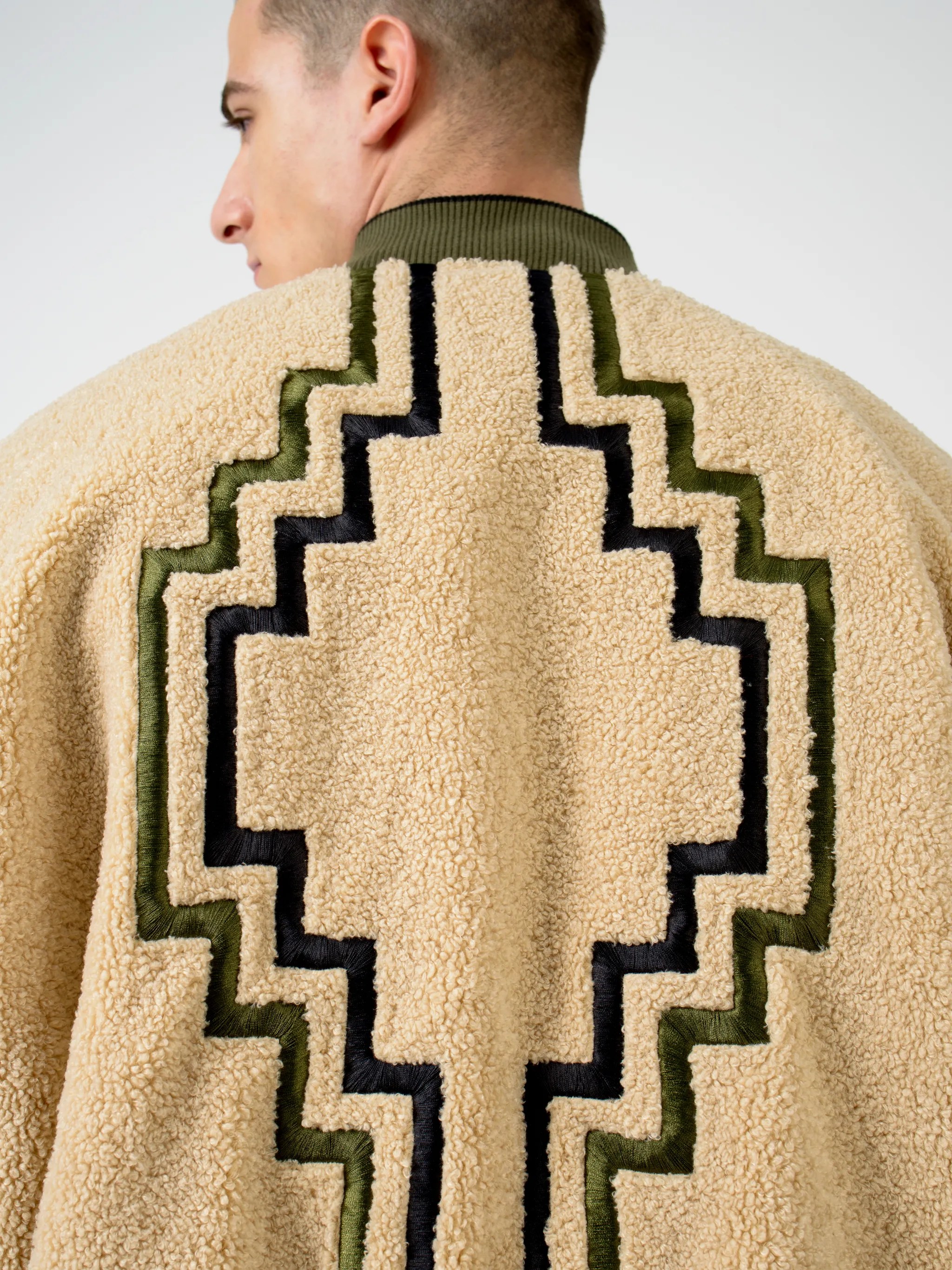 Army green/beige/black reversible panelled bomber jacket from Marcelo Burlon County of Milan featuring reversible, panelled design, embroidered logo to the rear, embroidered logo at the chest, ruched detailing, long sleeves, front zip fastening, two side slit pockets and ribbed edge.