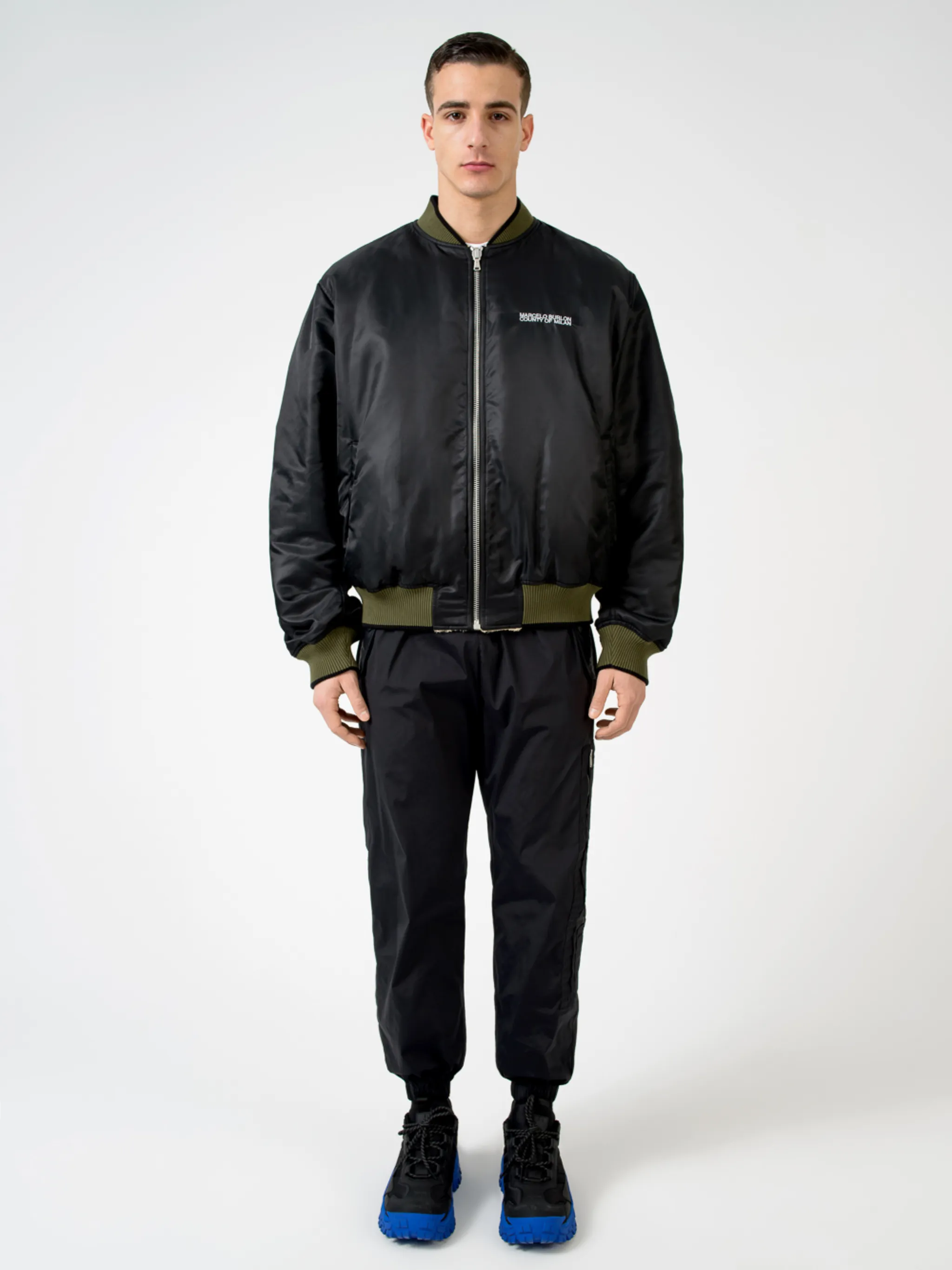 Army green/beige/black reversible panelled bomber jacket from Marcelo Burlon County of Milan featuring reversible, panelled design, embroidered logo to the rear, embroidered logo at the chest, ruched detailing, long sleeves, front zip fastening, two side slit pockets and ribbed edge.