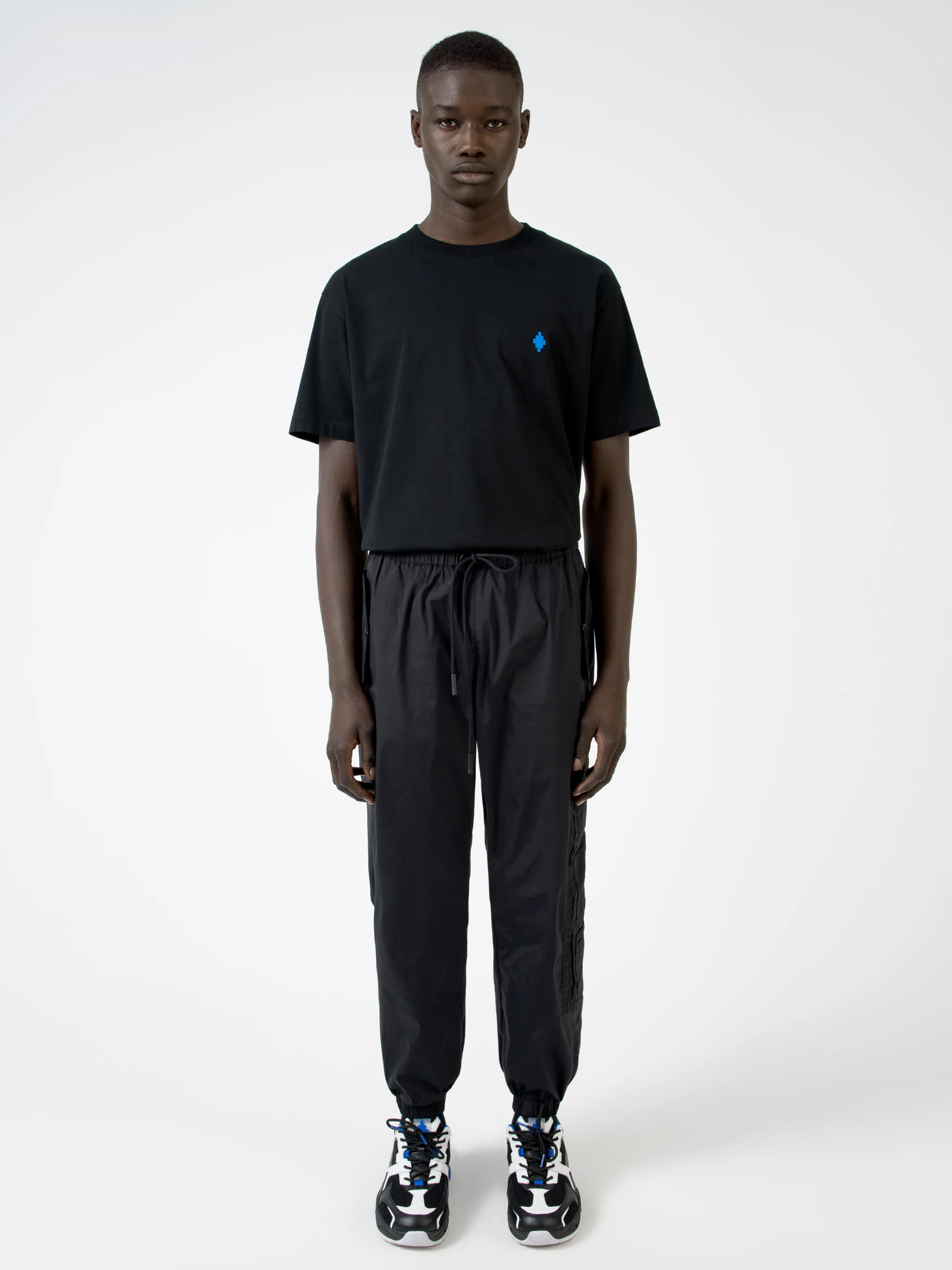 Black Cross tapered track pants from Marcelo Burlon County of Milan featuring embroidered logo to the front, elasticated ankles, elasticated waistband, tapered fit, two side slit pockets and two zip-fastening pockets to the side.