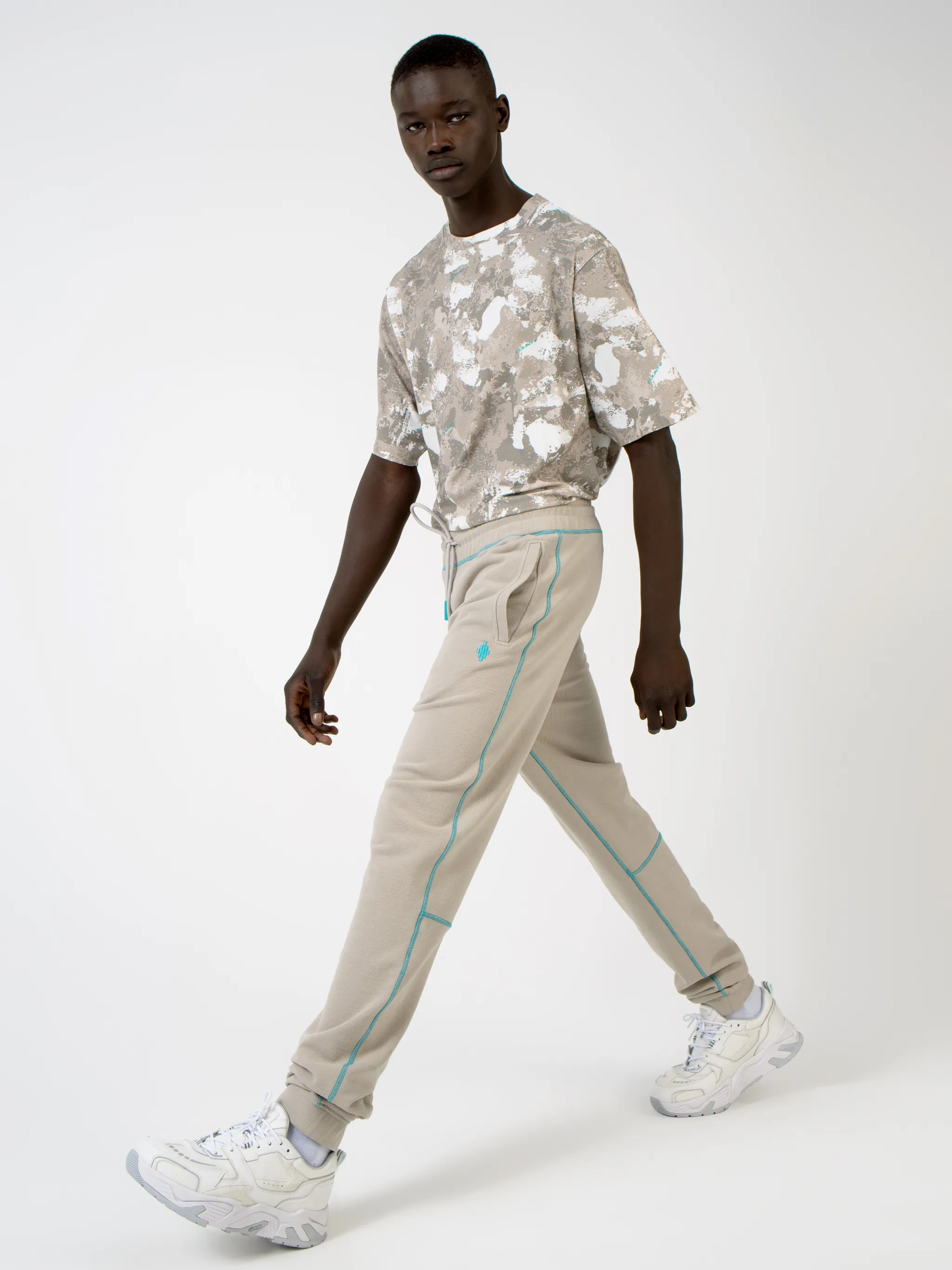Beige cotton Cross tapered track pants from Marcelo Burlon County of Milan featuring embroidered logo to the rear, contrasting trim, elasticated ankles, elasticated waistband, drawstring fastening, tapered design, two side slit pockets and rear welt pocket.