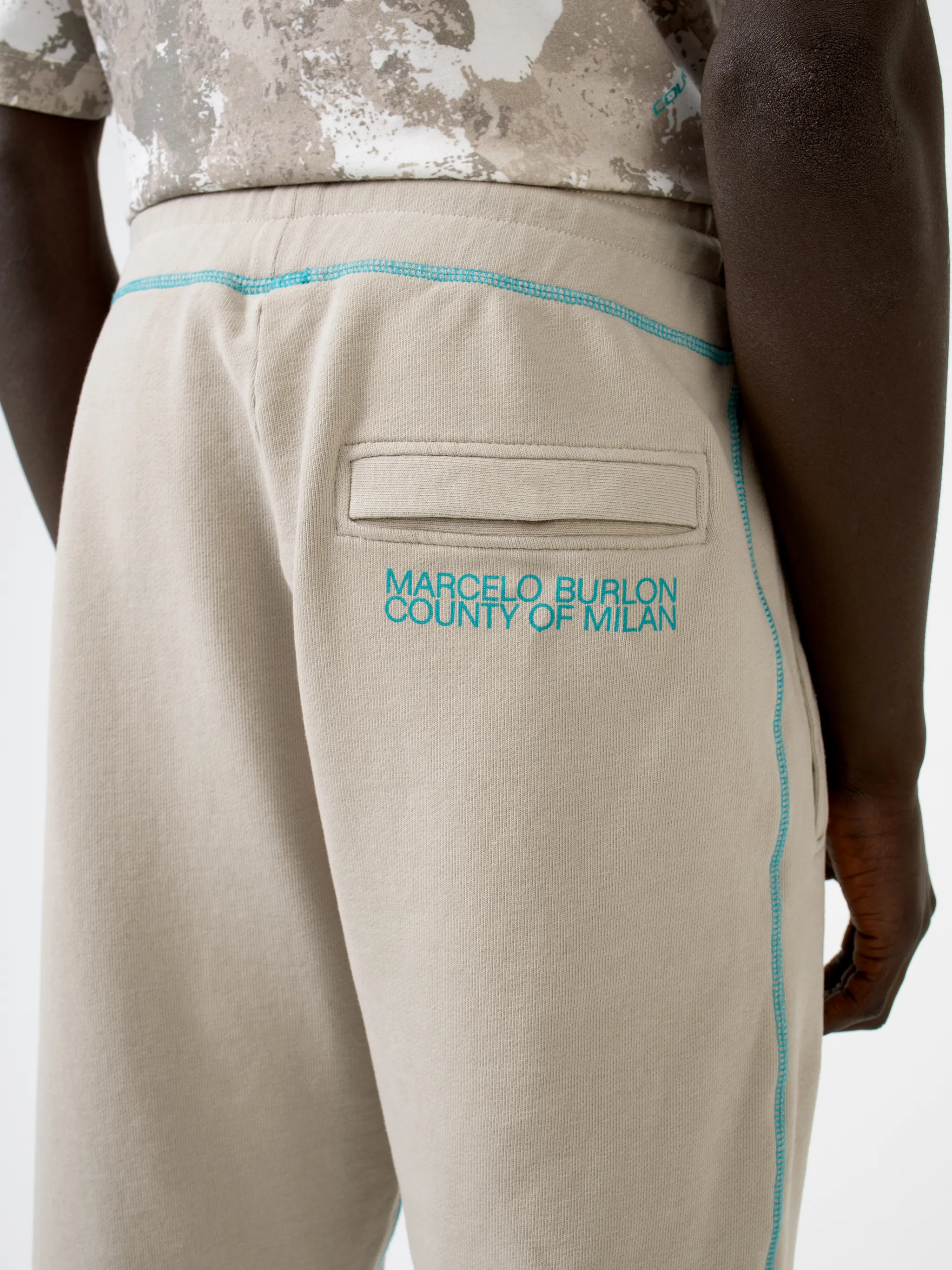 Beige cotton Cross tapered track pants from Marcelo Burlon County of Milan featuring embroidered logo to the rear, contrasting trim, elasticated ankles, elasticated waistband, drawstring fastening, tapered design, two side slit pockets and rear welt pocket.