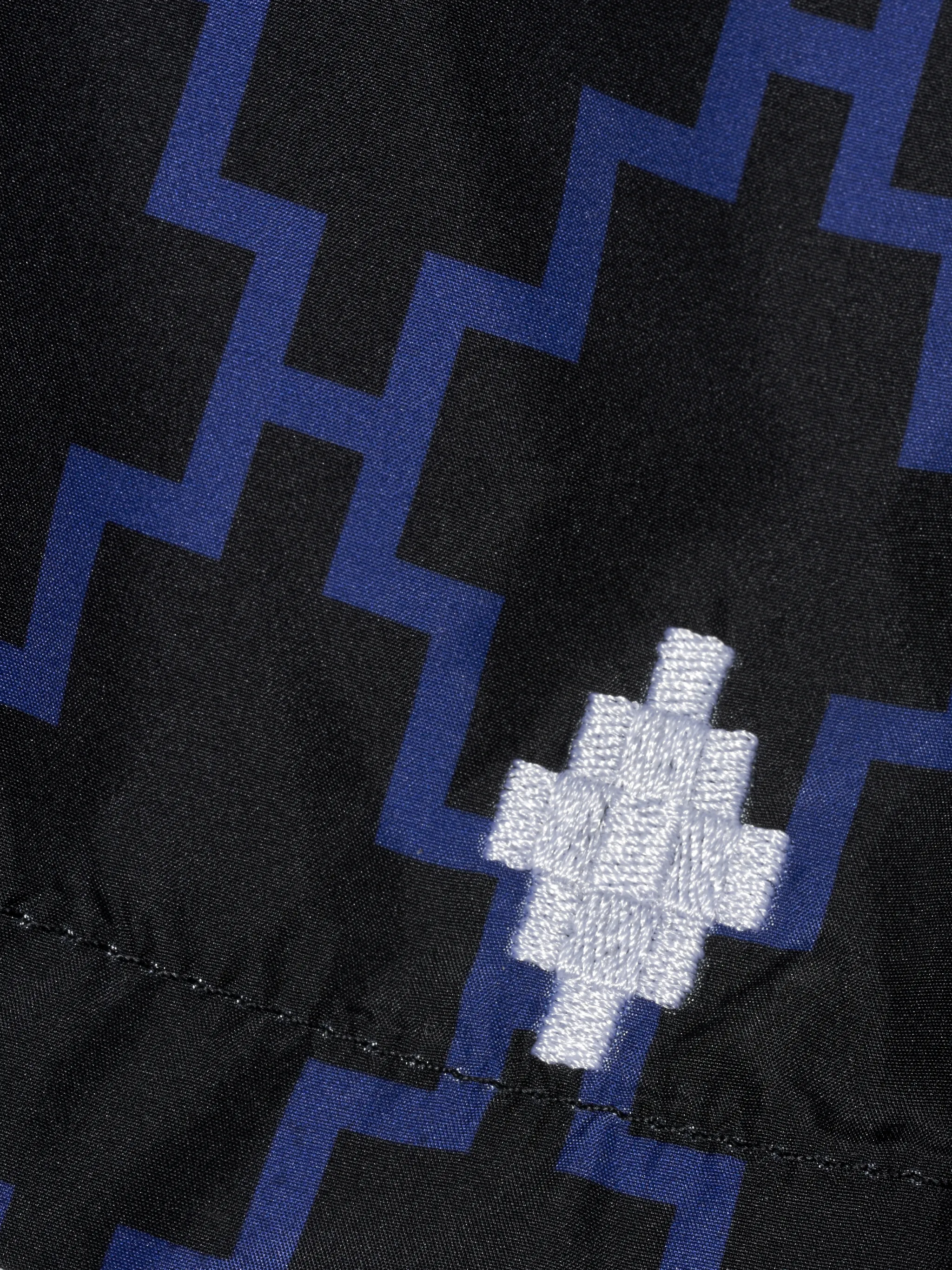 Black and blue cross pattern swimming shorts from Marcelo Burlon County of Milan featuring elasticated waistband, drawstring fastening, two side slit pockets, embroidered logo to the front, rear pouch pocket and eyelet detailing. Be mindful to try on swimwear over your own garments..
