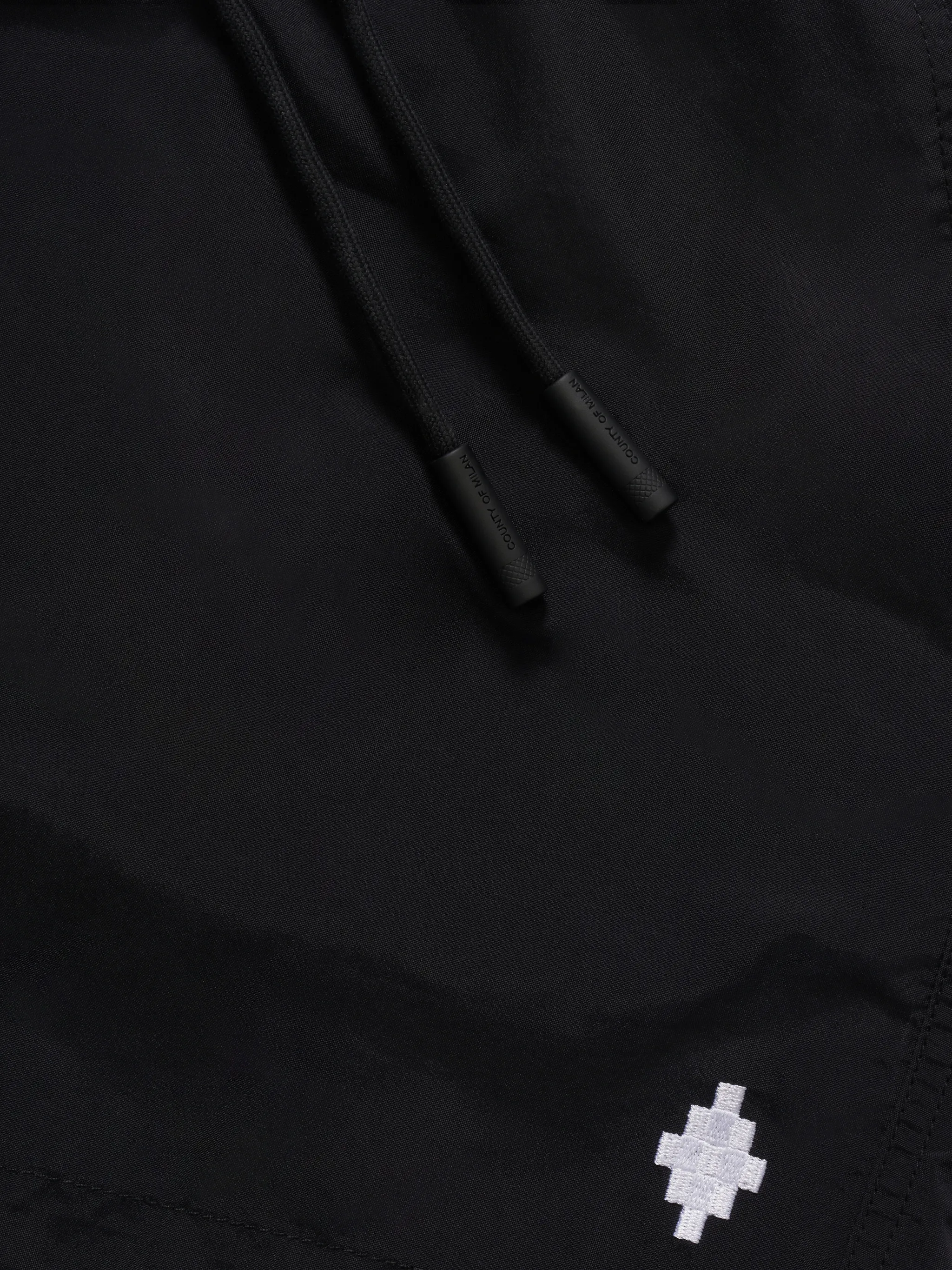 Black cross-logo swimming shorts from Marcelo Burlon County of Milan featuring logo print at the leg, elasticated drawstring waistband, two side slit pockets and logo patch to the rear. Be mindful to try on swimwear over your own garments..