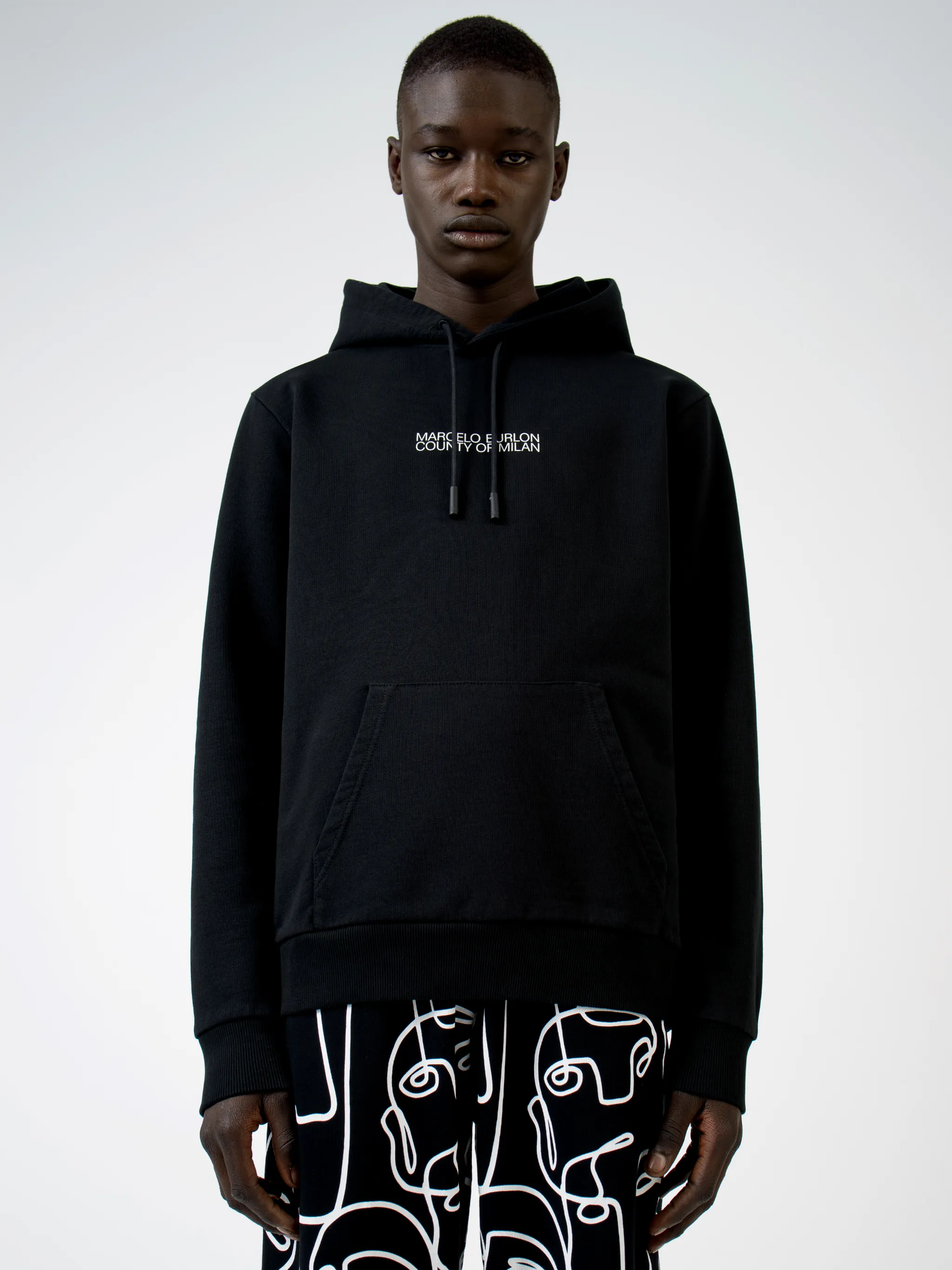 Black cotton logo print hoodie from MARCELO BURLON COUNTY OF MILAN featuring drawstring hood, logo print to the front, long sleeves, abstract pattern print, kangaroo pocket and loose fit.