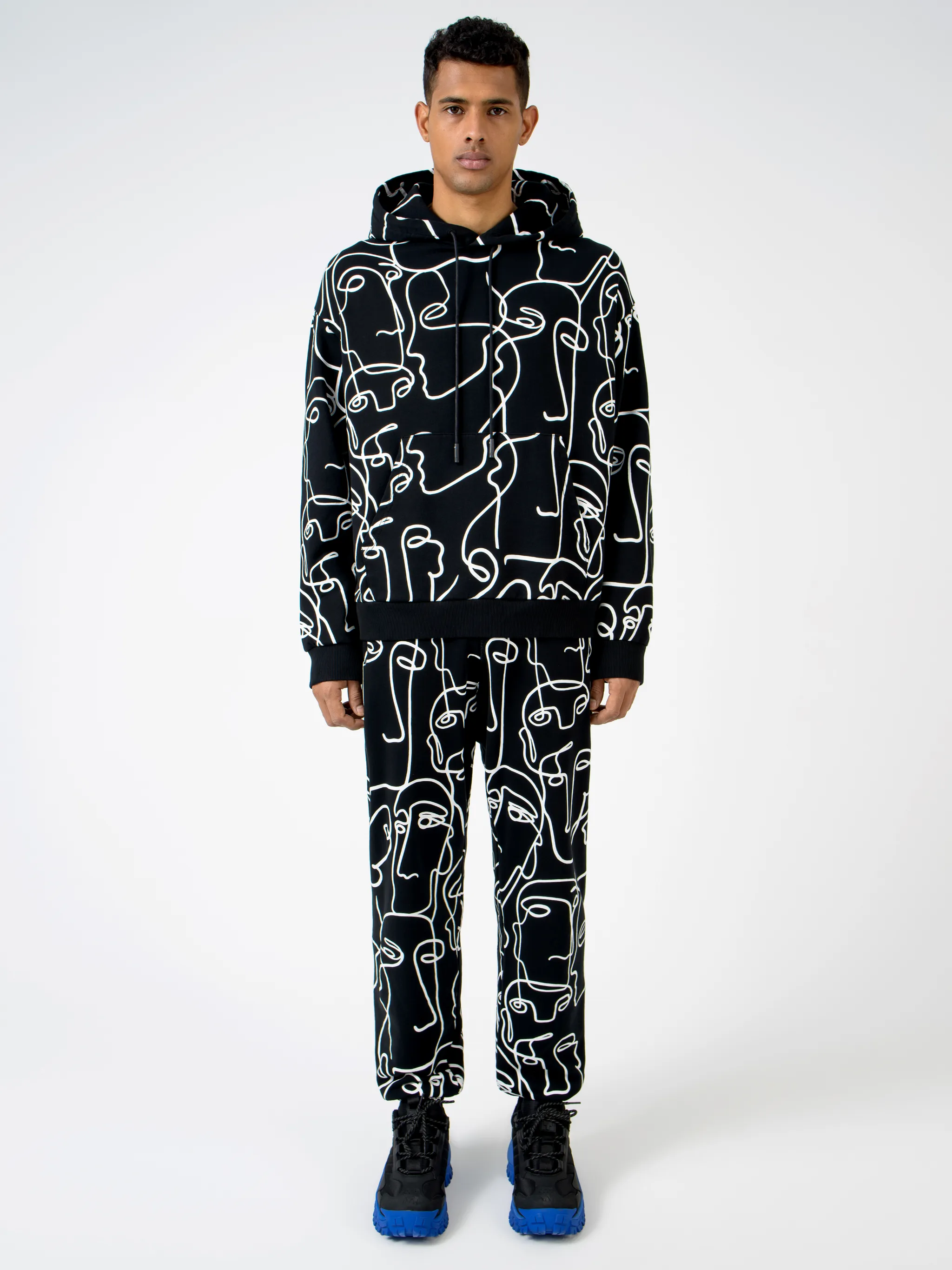 Black/white cotton all-over Faces print hoodie from Marcelo Burlon County of Milan featuring all-over logo print, drawstring hood, two front pouch pockets, long sleeves and straight hem.