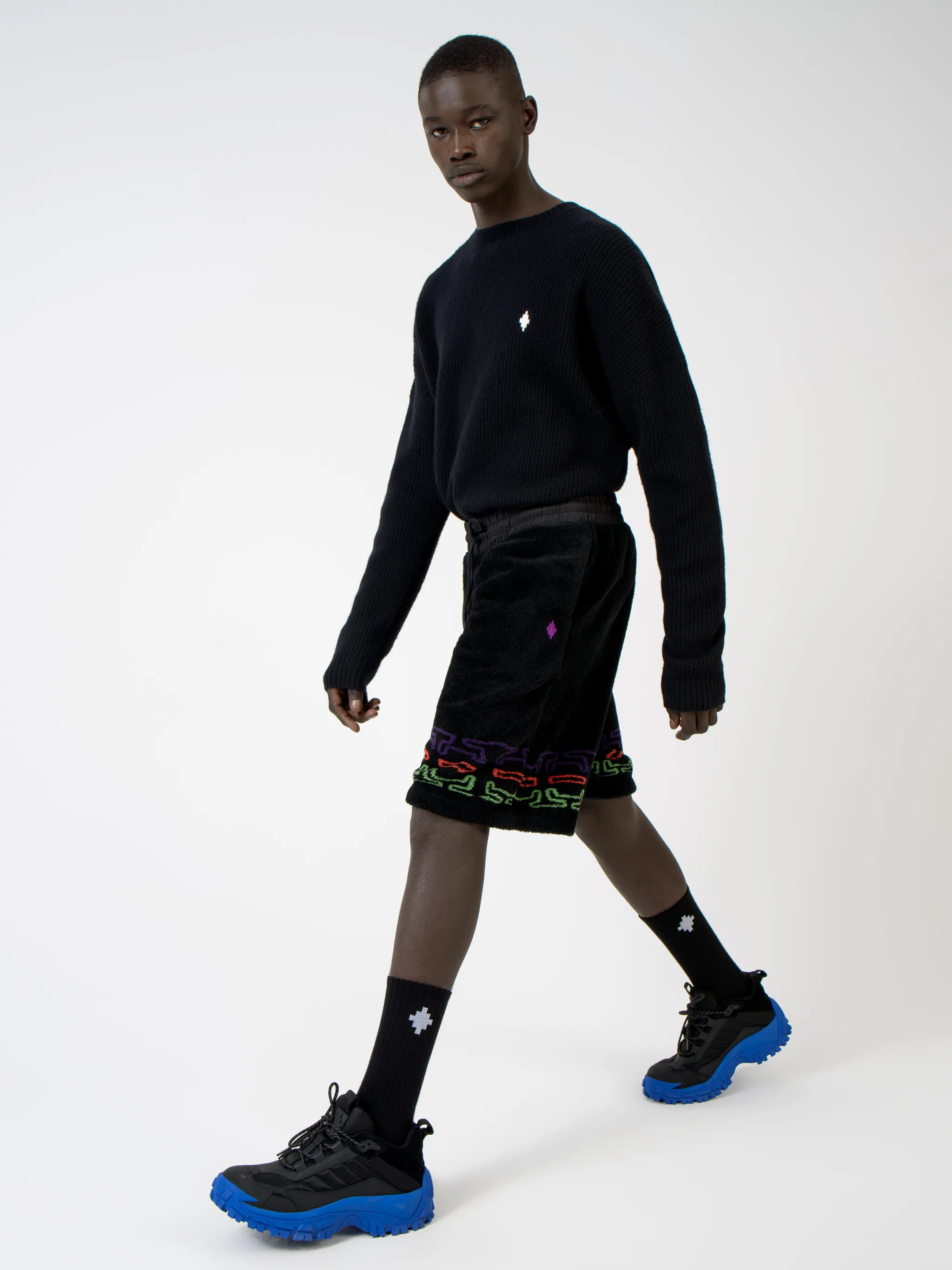 Black/multicolour logo print fleece track shorts from Marcelo Burlon County of Milan featuring jersey fleece, logo print embellishment, elasticated waistband, drawstring fastening, two side pouch pockets and rear welt pocket.