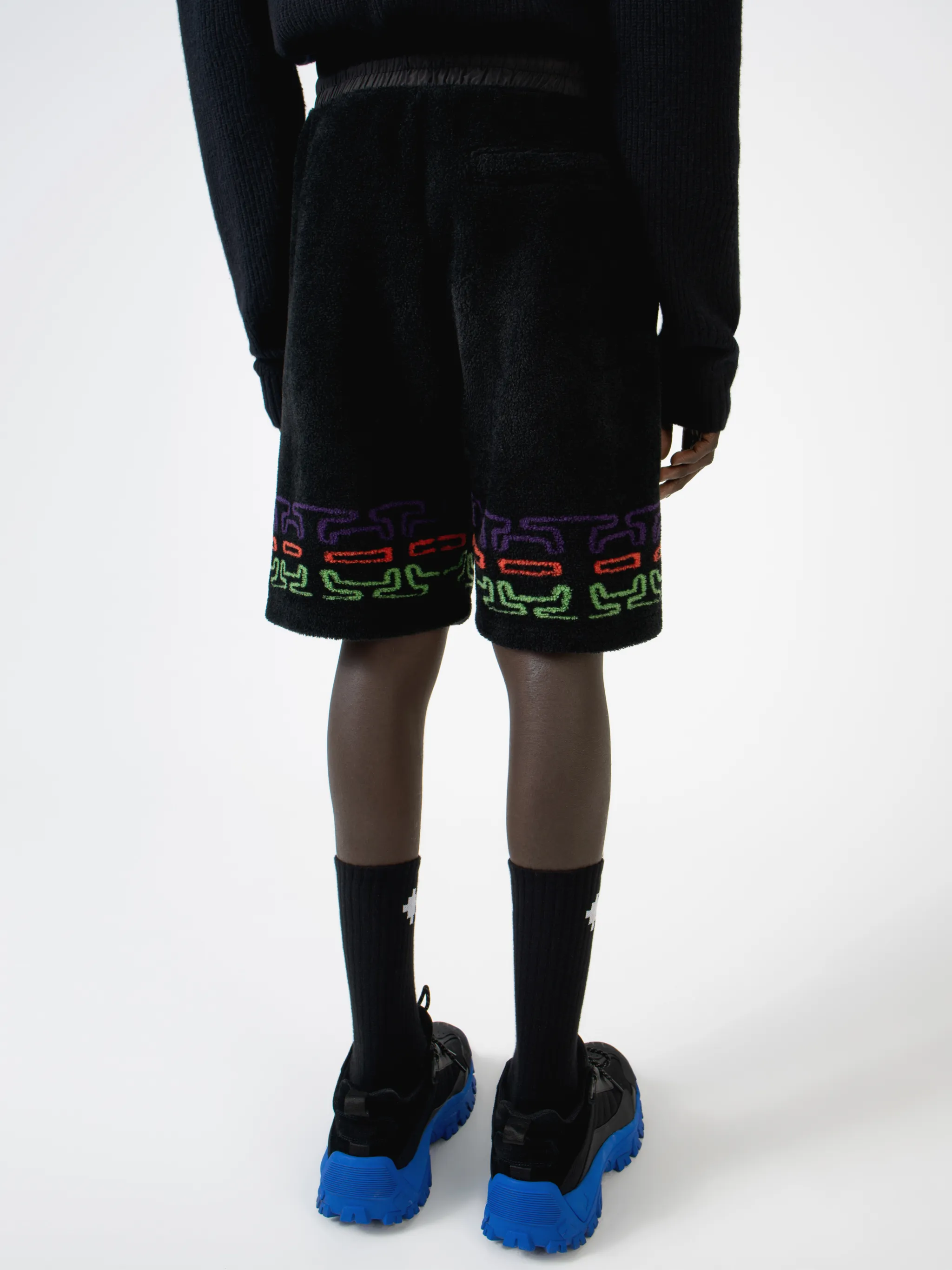 Black/multicolour logo print fleece track shorts from Marcelo Burlon County of Milan featuring jersey fleece, logo print embellishment, elasticated waistband, drawstring fastening, two side pouch pockets and rear welt pocket.