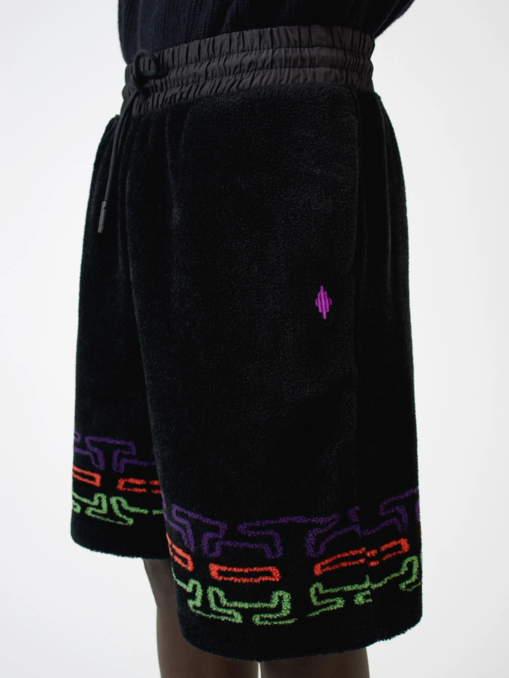 Black/multicolour logo print fleece track shorts from Marcelo Burlon County of Milan featuring jersey fleece, logo print embellishment, elasticated waistband, drawstring fastening, two side pouch pockets and rear welt pocket.