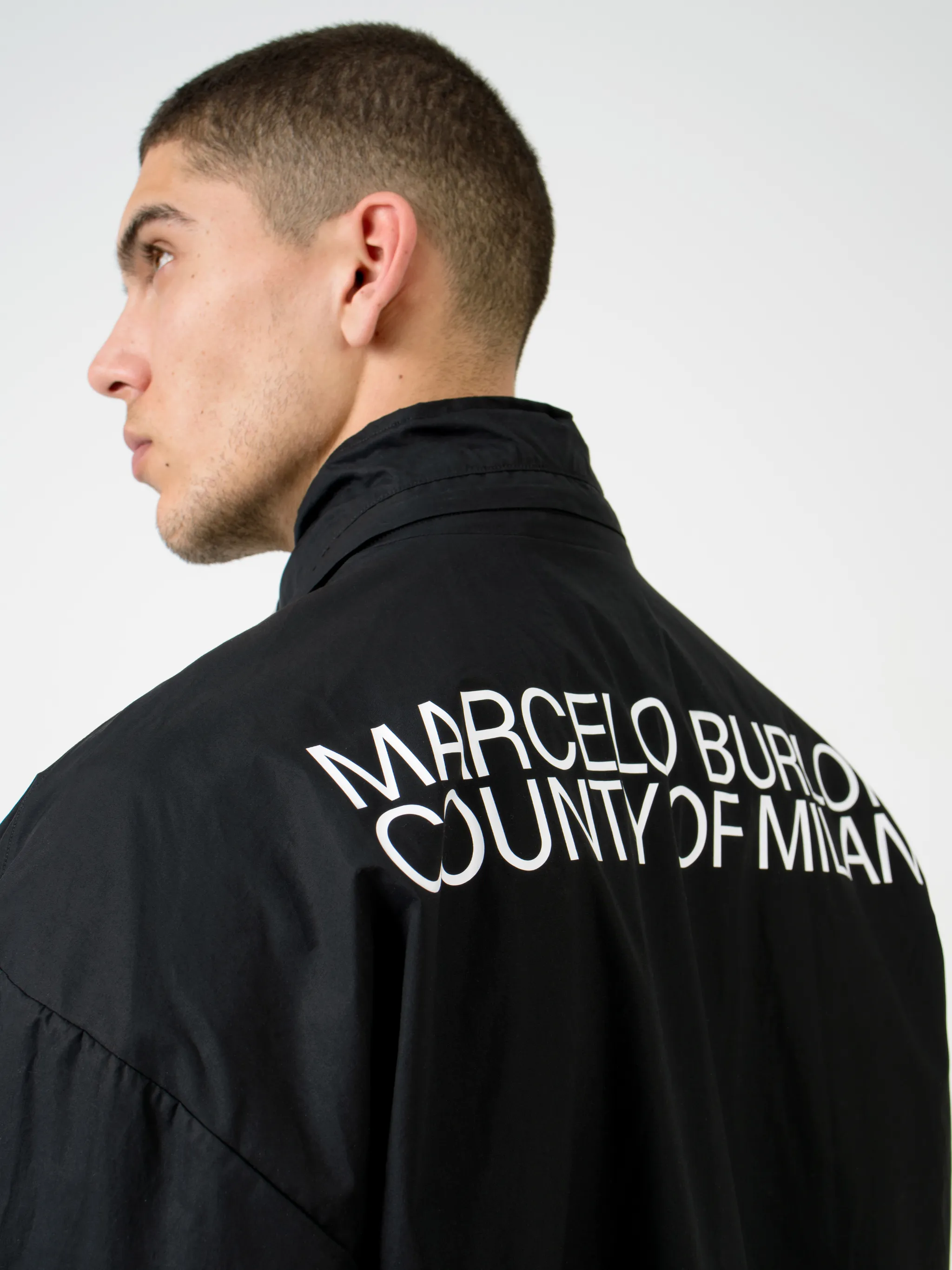 Black cotton-blend logo-print zip-up track jacket from Marcelo Burlon County of Milan featuring logo print to the rear, concealed hood, high neck, front zip fastening, long sleeves, elasticated cuffs and elasticated hem.