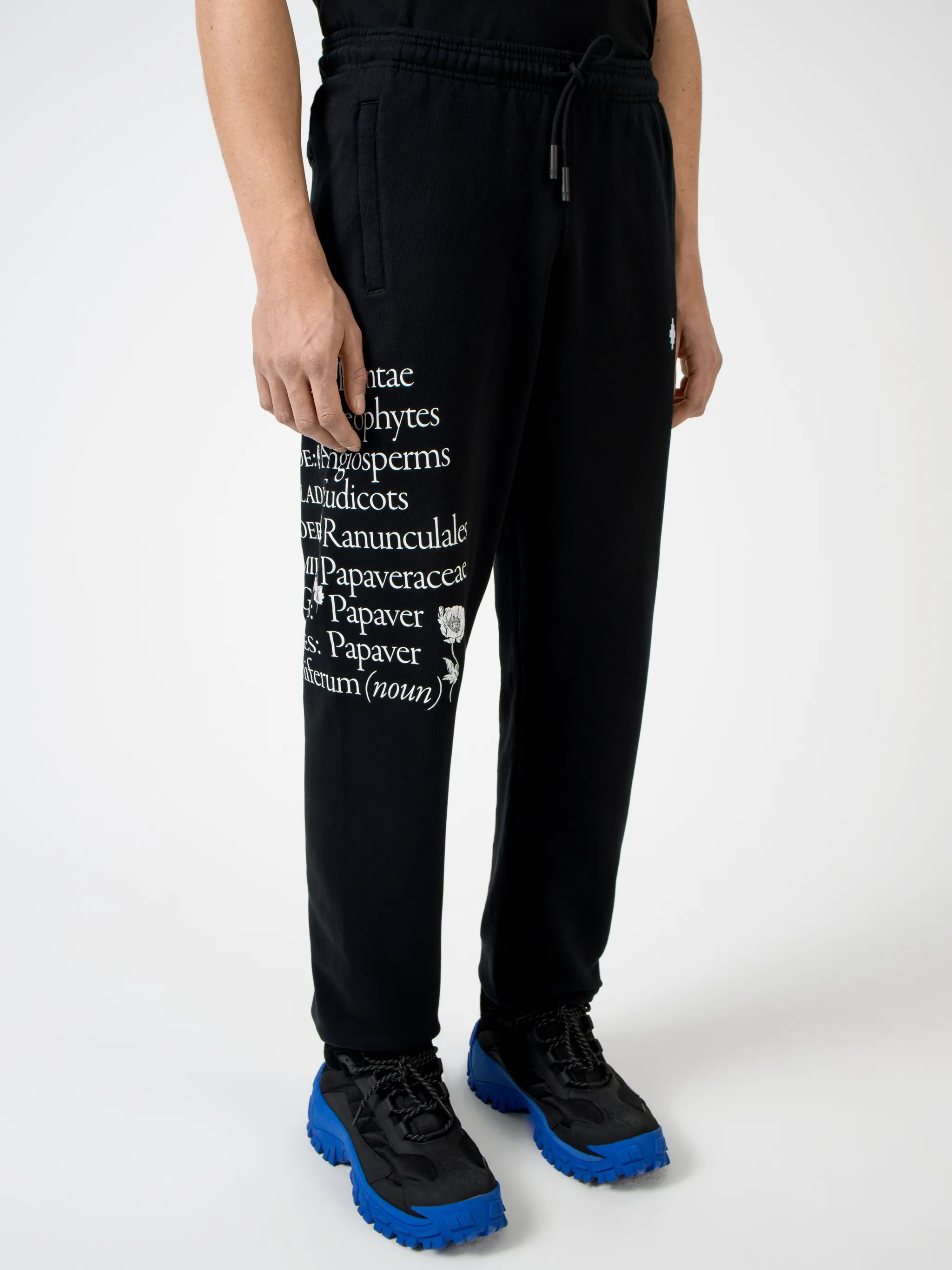 Black cotton Papaver tapered track pants from Marcelo Burlon County of Milan featuring embroidered logo to the front, slogan print, elasticated ankles, elasticated waistband, drawstring fastening, tapered design, two side slit pockets and rear welt pocket.