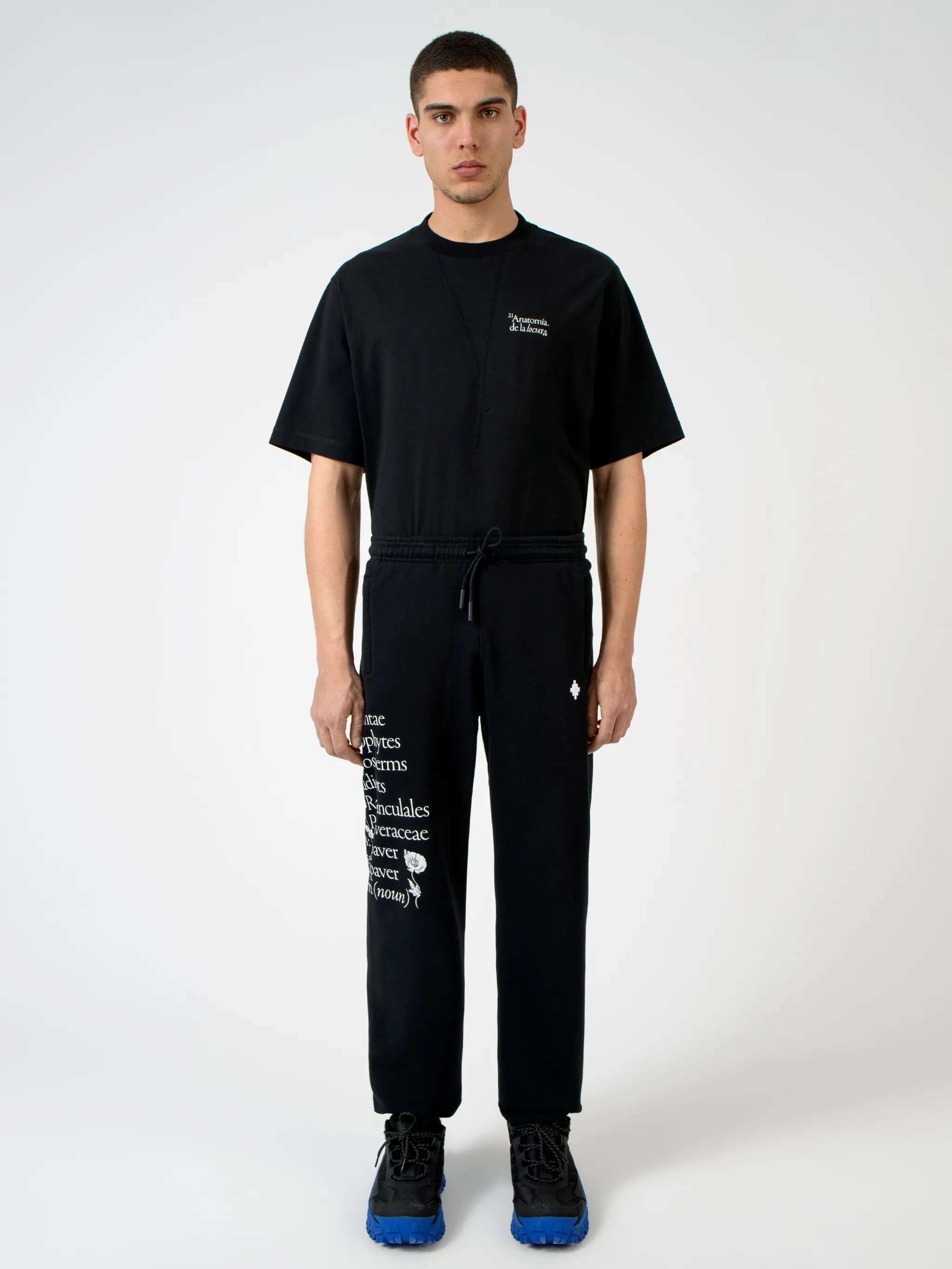 Black cotton Papaver tapered track pants from Marcelo Burlon County of Milan featuring embroidered logo to the front, slogan print, elasticated ankles, elasticated waistband, drawstring fastening, tapered design, two side slit pockets and rear welt pocket.