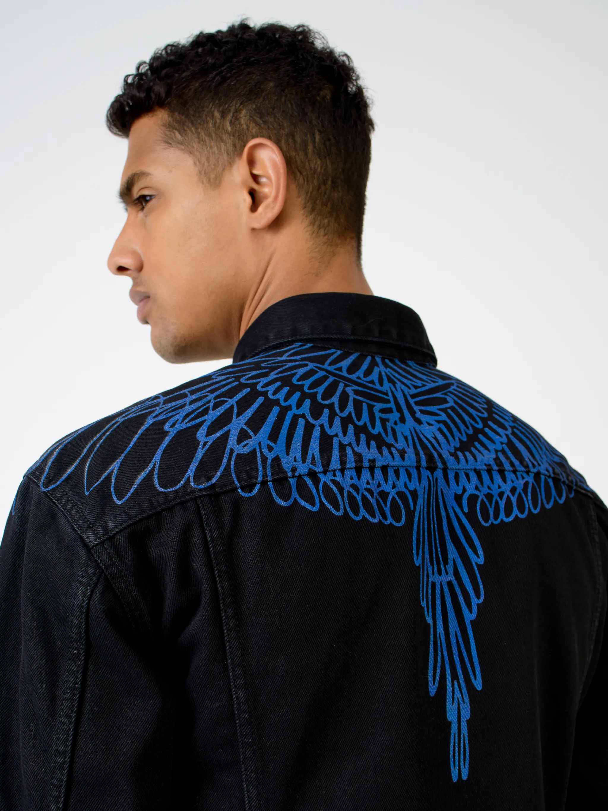 Black/blue cotton Pictorial Wings denim jacket from Marcelo Burlon County of Milan featuring wings print, front button placket, two chest flap pockets, two side slit pockets, long sleeves, buttoned cuffs and logo patch to the rear.
