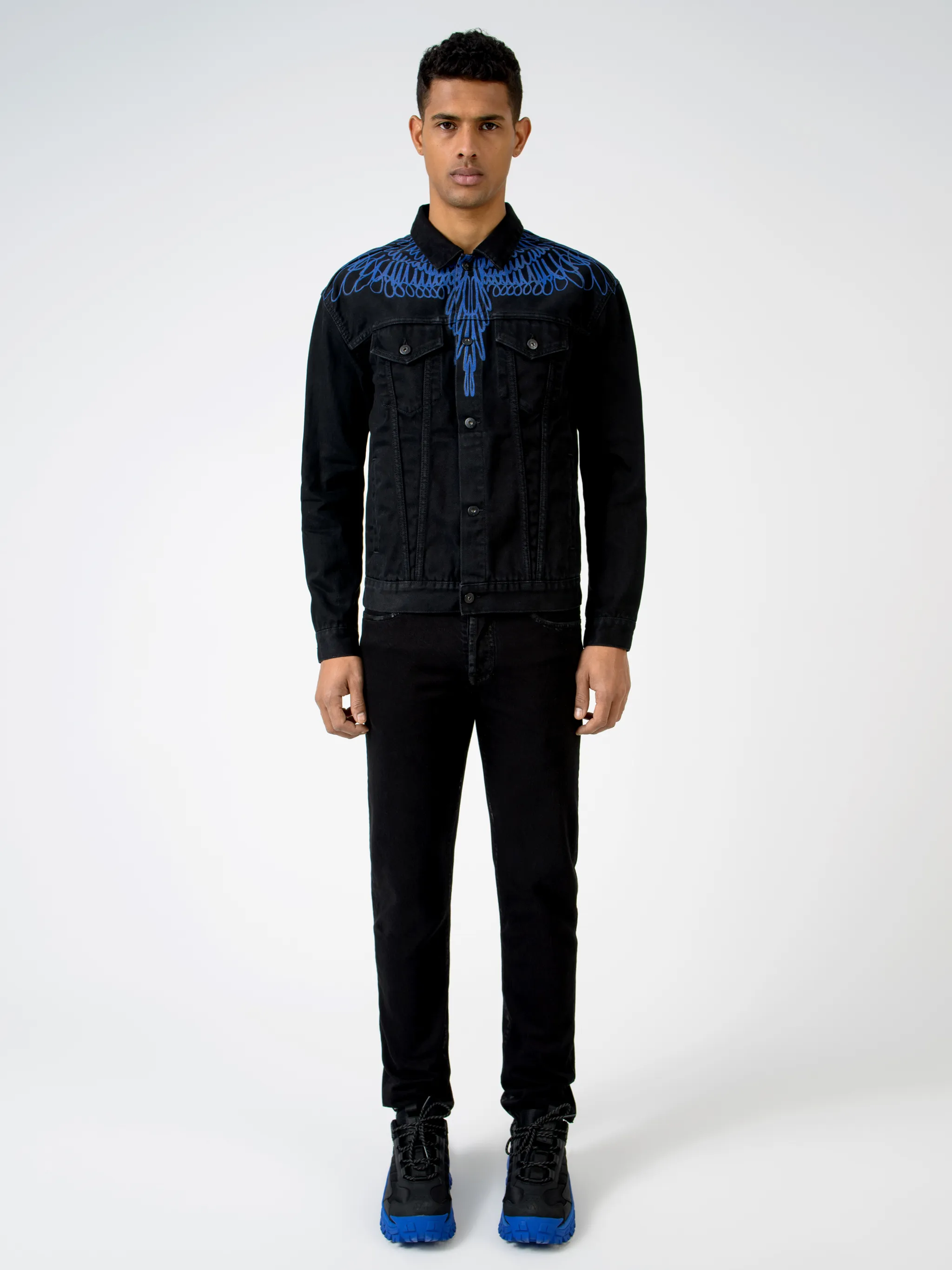 Black/blue cotton Pictorial Wings denim jacket from Marcelo Burlon County of Milan featuring wings print, front button placket, two chest flap pockets, two side slit pockets, long sleeves, buttoned cuffs and logo patch to the rear.