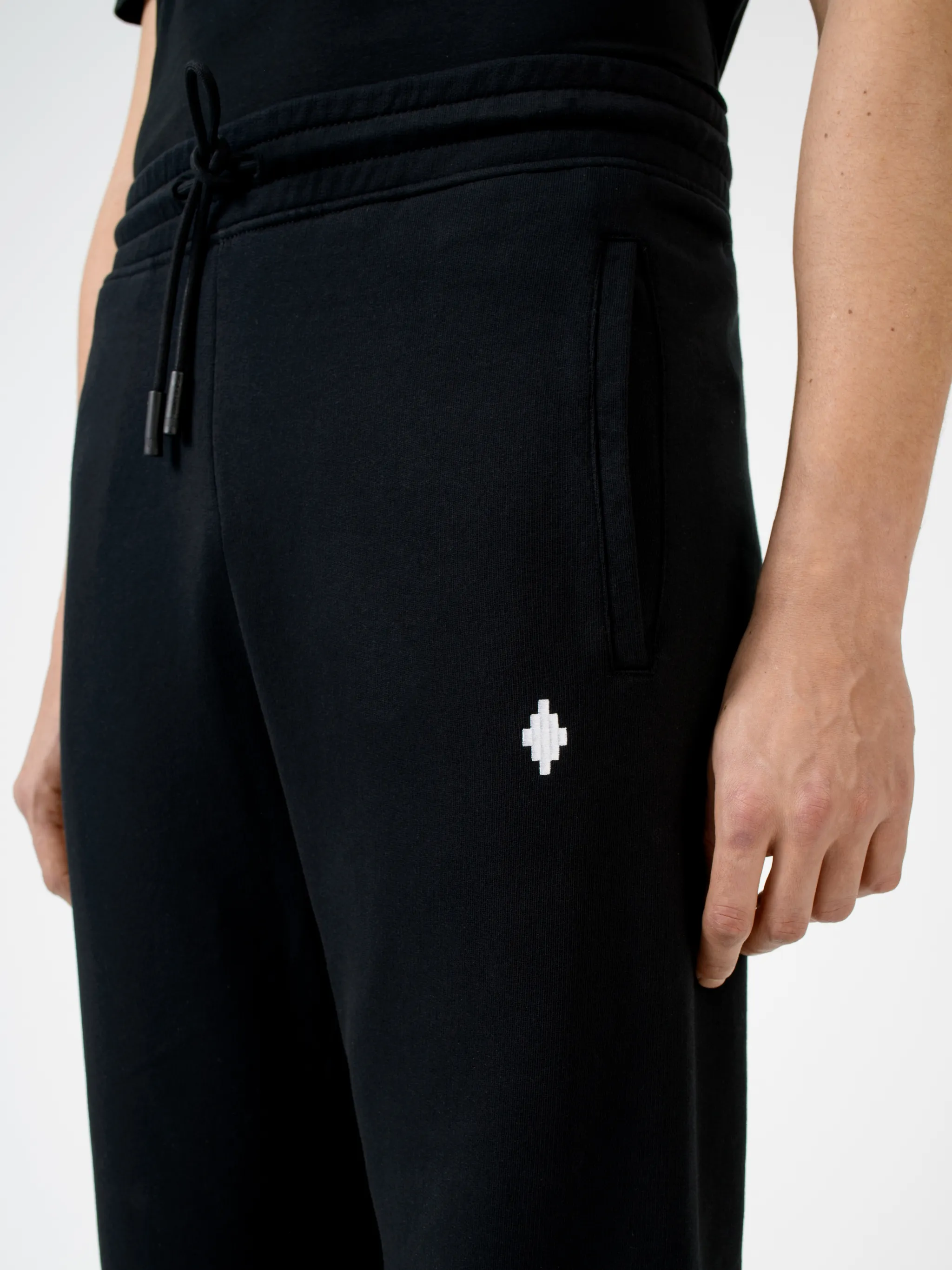 Black cotton Wings tapered-fit track pants from Marcelo Burlon County of Milan featuring wings print, elasticated ankles, elasticated waistband, drawstring fastening, tapered design, two side slash pockets and rear patch pocket.