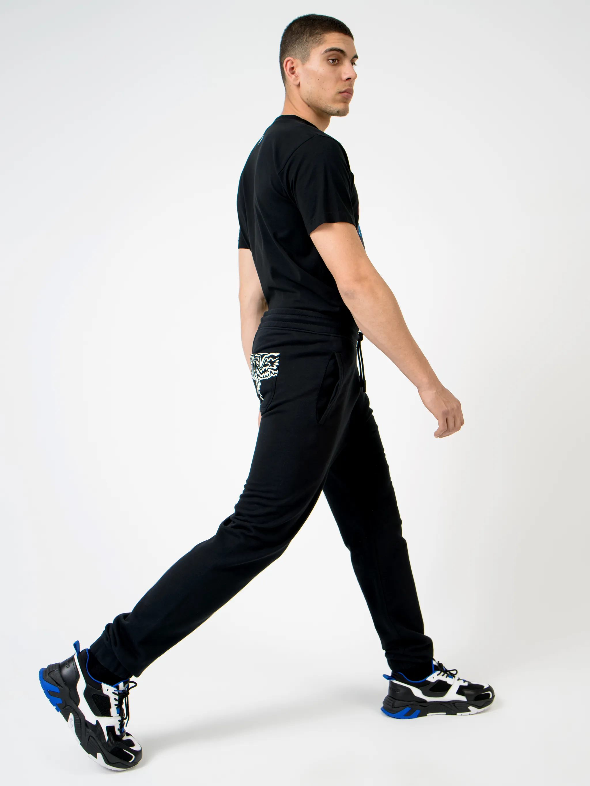 Black cotton Wings tapered-fit track pants from Marcelo Burlon County of Milan featuring wings print, elasticated ankles, elasticated waistband, drawstring fastening, tapered design, two side slash pockets and rear patch pocket.
