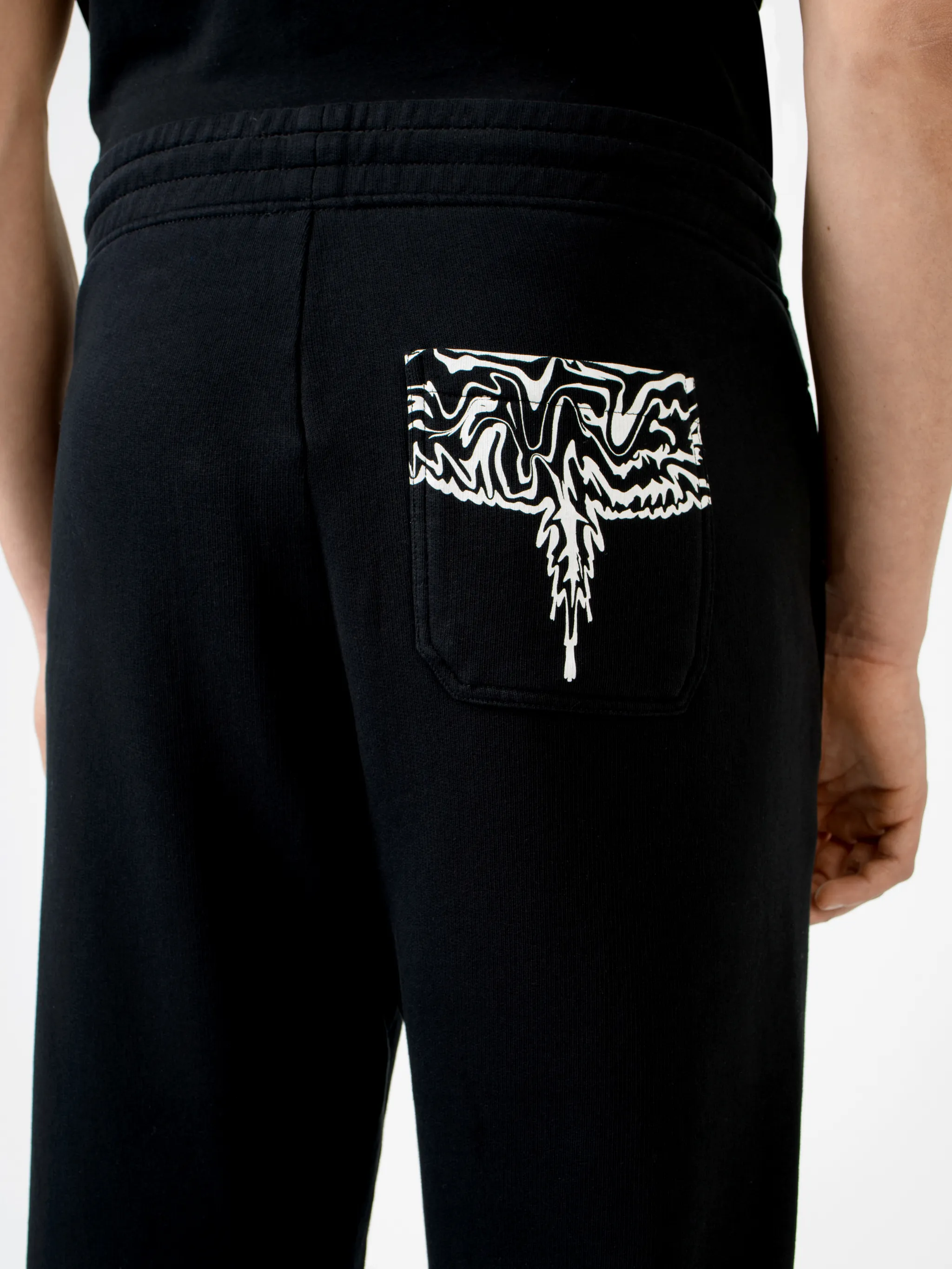Black cotton rear Psychedelic Wings track pants from Marcelo Burlon County of Milan featuring wings print, elasticated waistband, drawstring fastening, embroidered logo, two side patch pockets, rear patch pocket and elasticated ankles.
