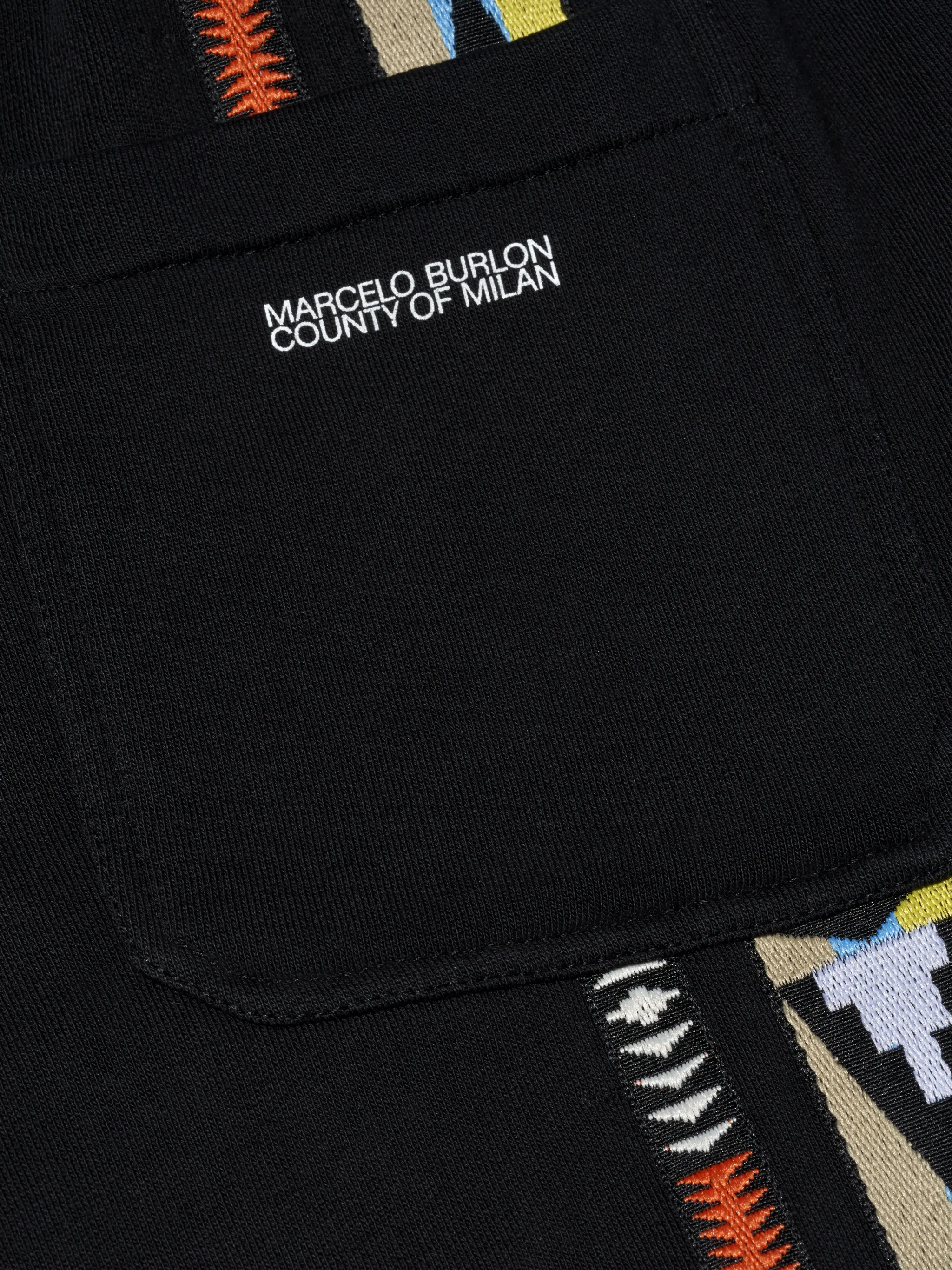 Black/multicolour geometric-pattern track pants from Marcelo Burlon County of Milan featuring drawstring waist, two side slit pockets, embroidered logo to the front, geometric embroidery, rear patch pocket, embroidered logo to the rear and elasticated ankles.