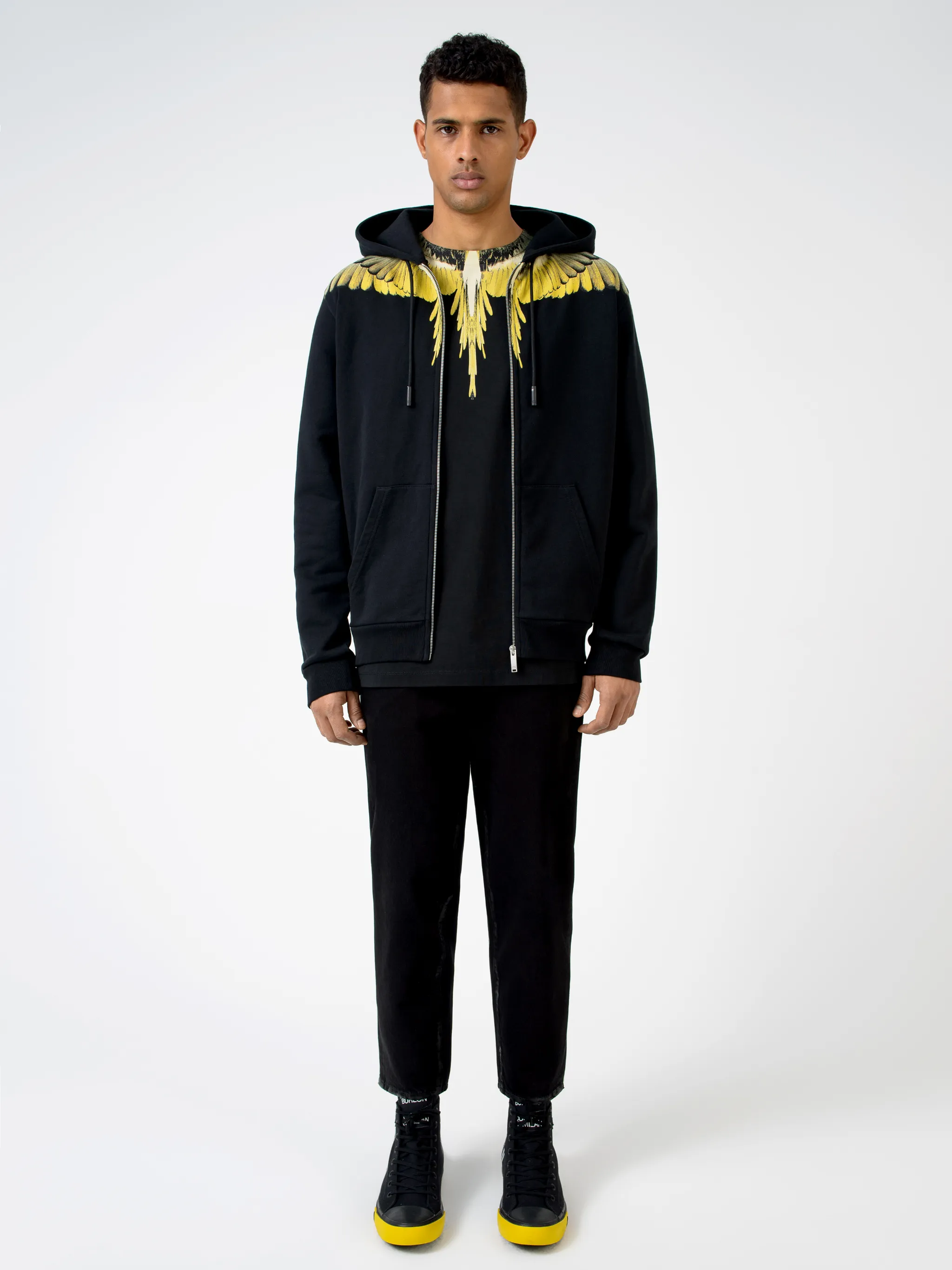 Black/yellow cotton Wings print hoodie from Marcelo Burlon County of Milan featuring drawstring hood, two side pouch pockets, long sleeves, front zip fastening and signature Wings print.